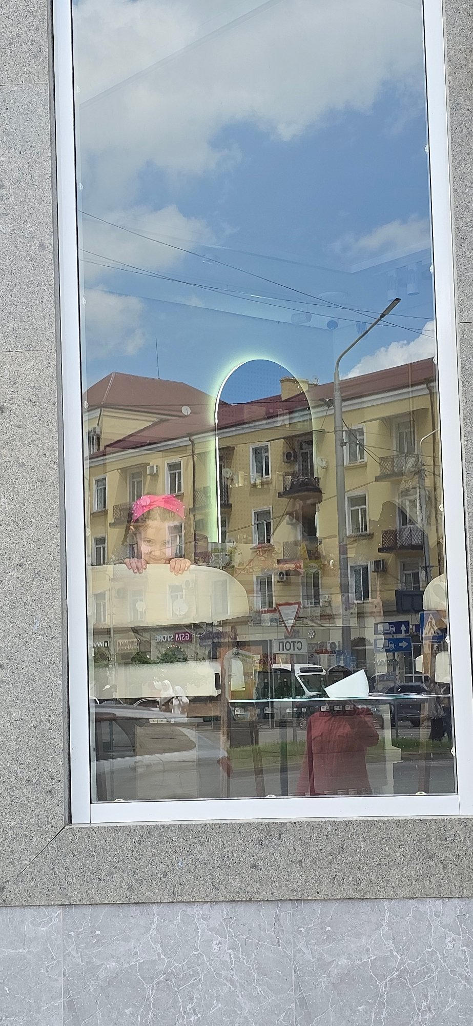 Street reflection captured in Grozny storefront window