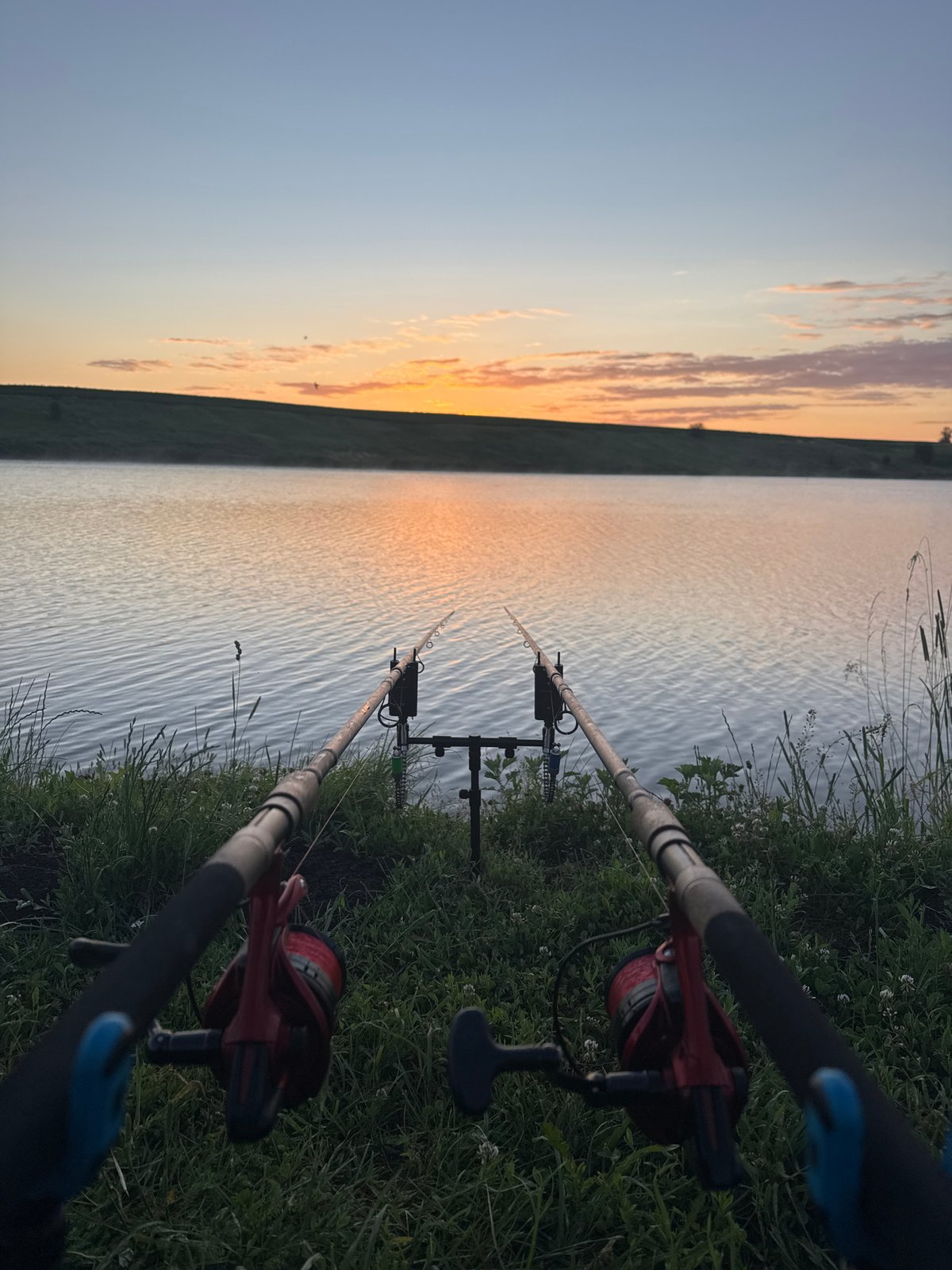 Fishing rods and a warm drink at a peaceful lakeside dusk