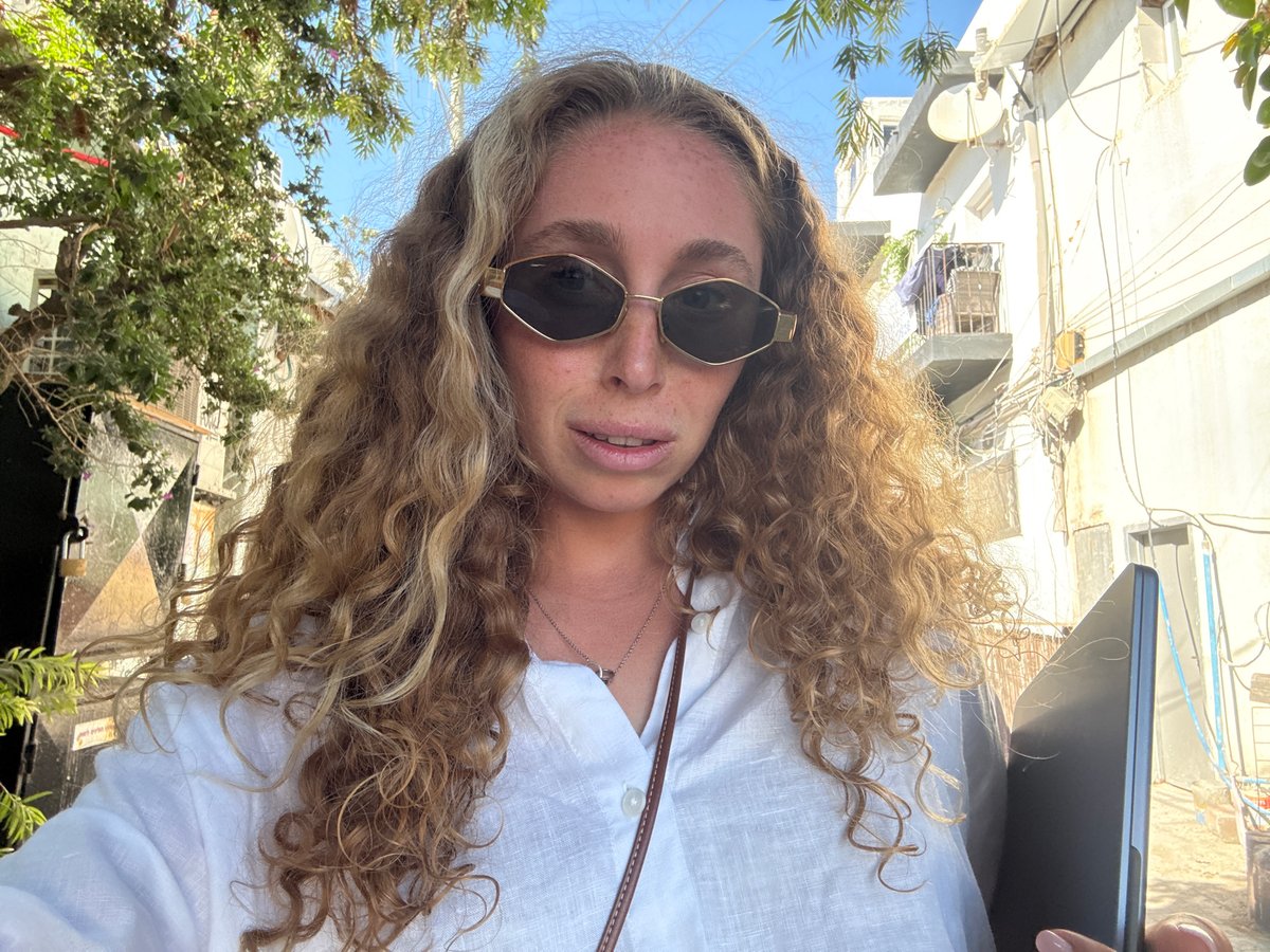 Low-angle portrait with laptop, white linen, sunglasses — Tel Aviv