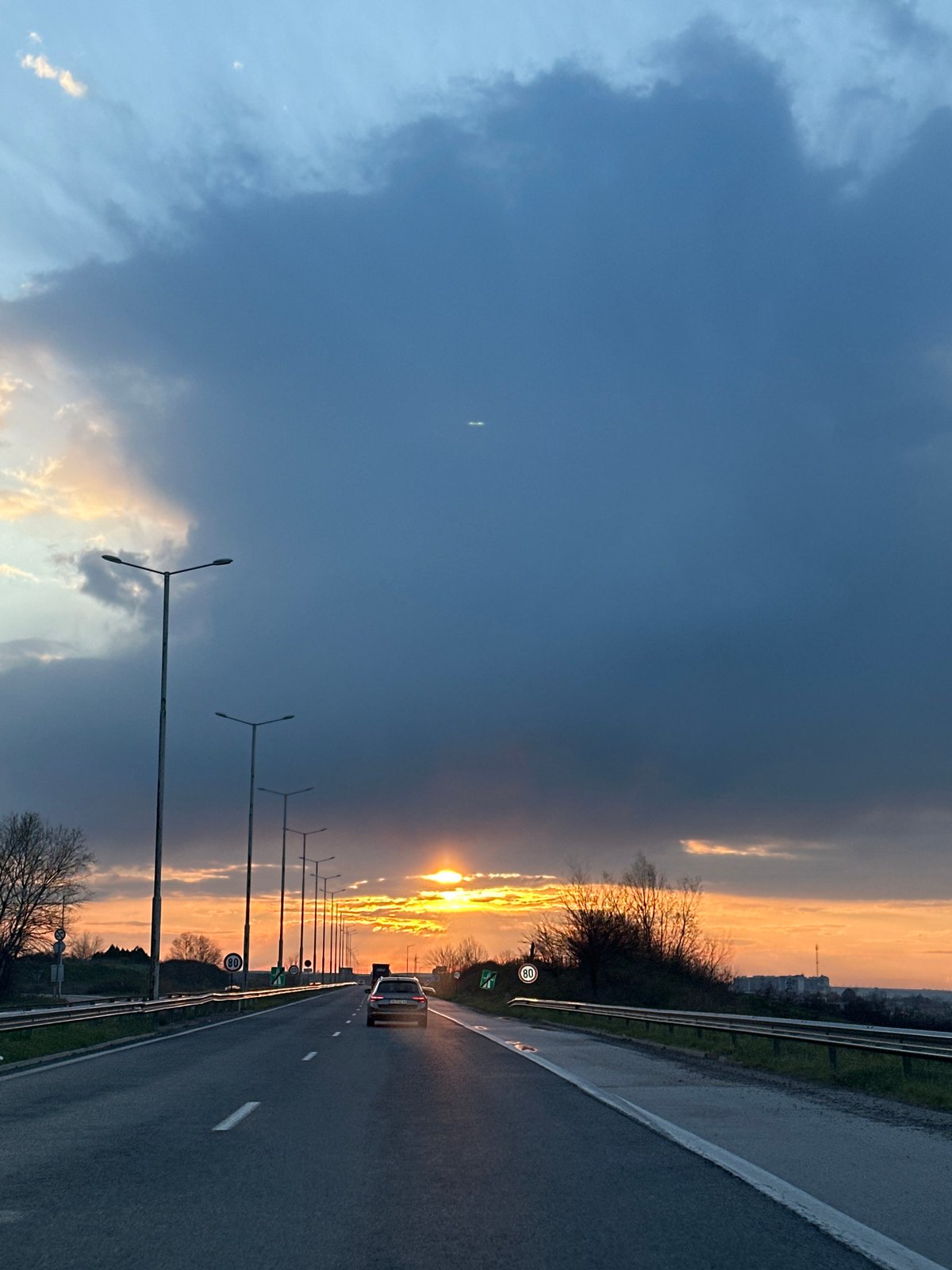 Car travels wet highway at sunset near Svilengrad, Bulgaria