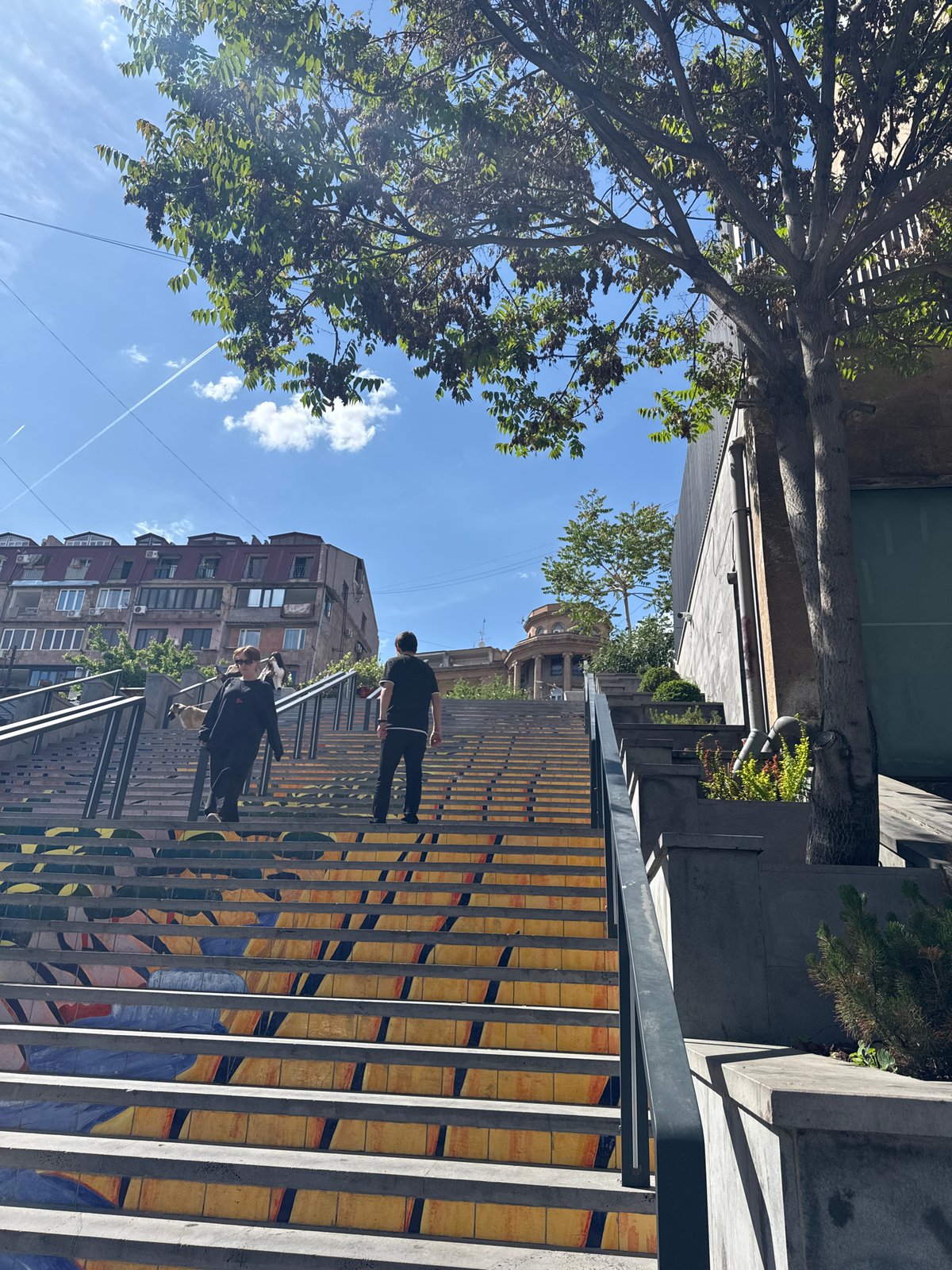 Two pedestrians climb Yerevan's Cascade monument stairs
