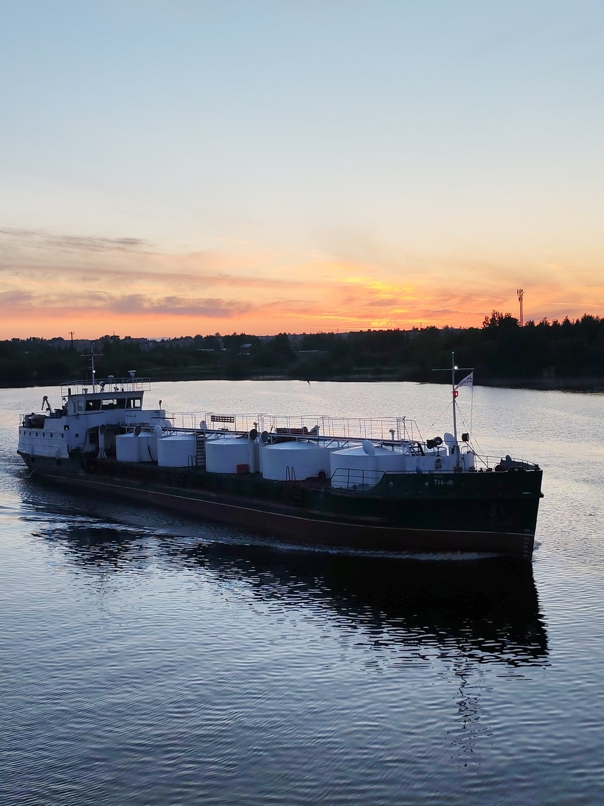 Commercial barges navigate river during dawn hours, witness documents traffic