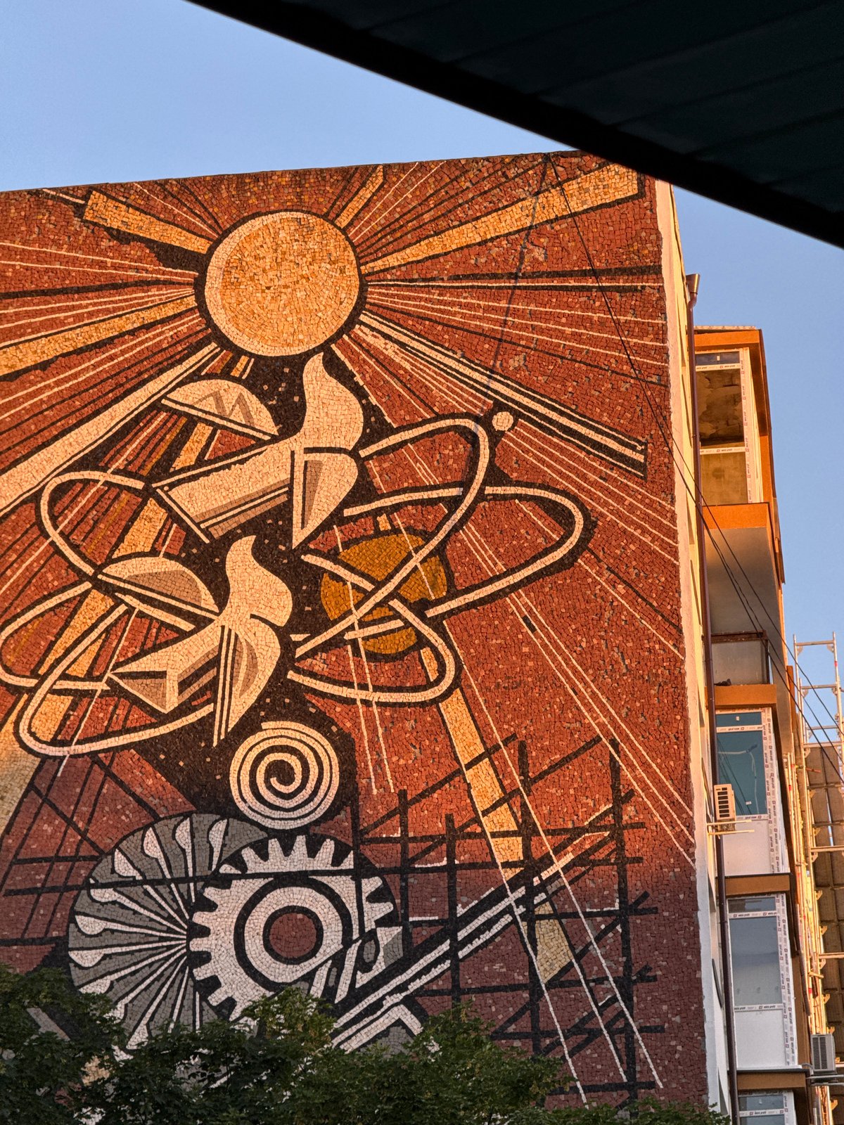 Golden sunset illuminates mosaic mural and trees in Lovech