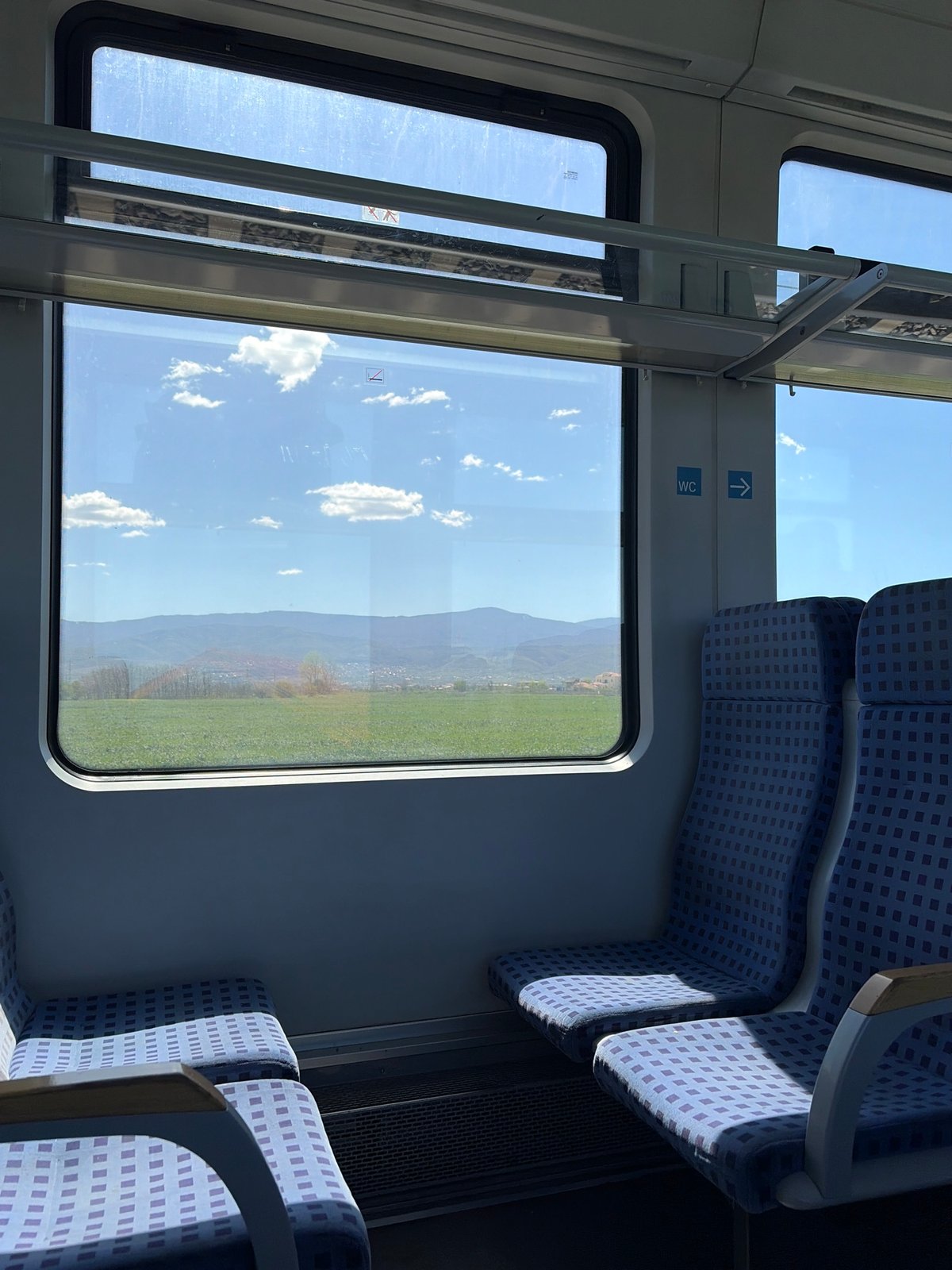 Train passengers observe countryside views, station platform activity documented