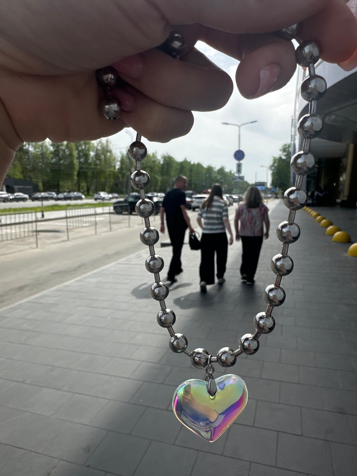 Person documents iridescent heart necklace in Nizhny Novgorod street scenes
