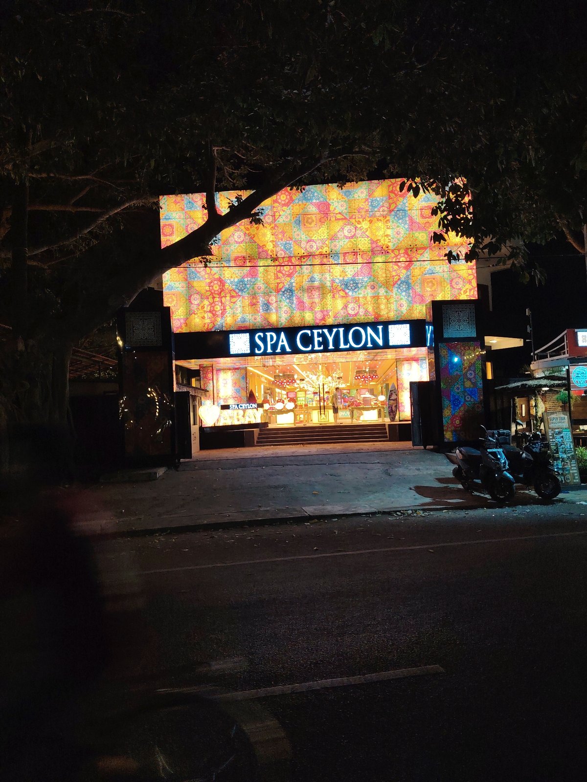 Evening stroll past lit storefronts and parked motorbikes