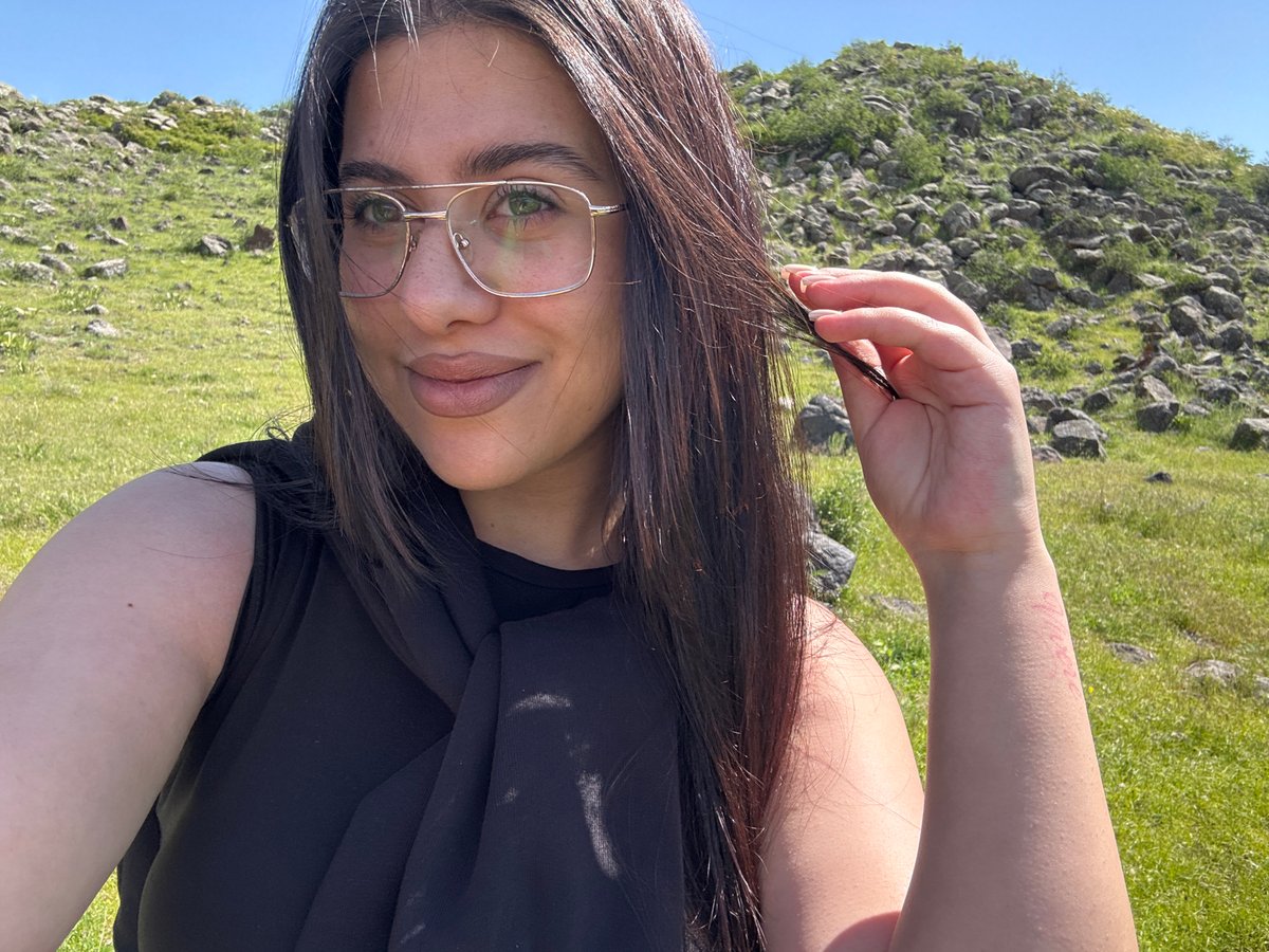 Woman with teal braids photographed across rural Armenian landscape