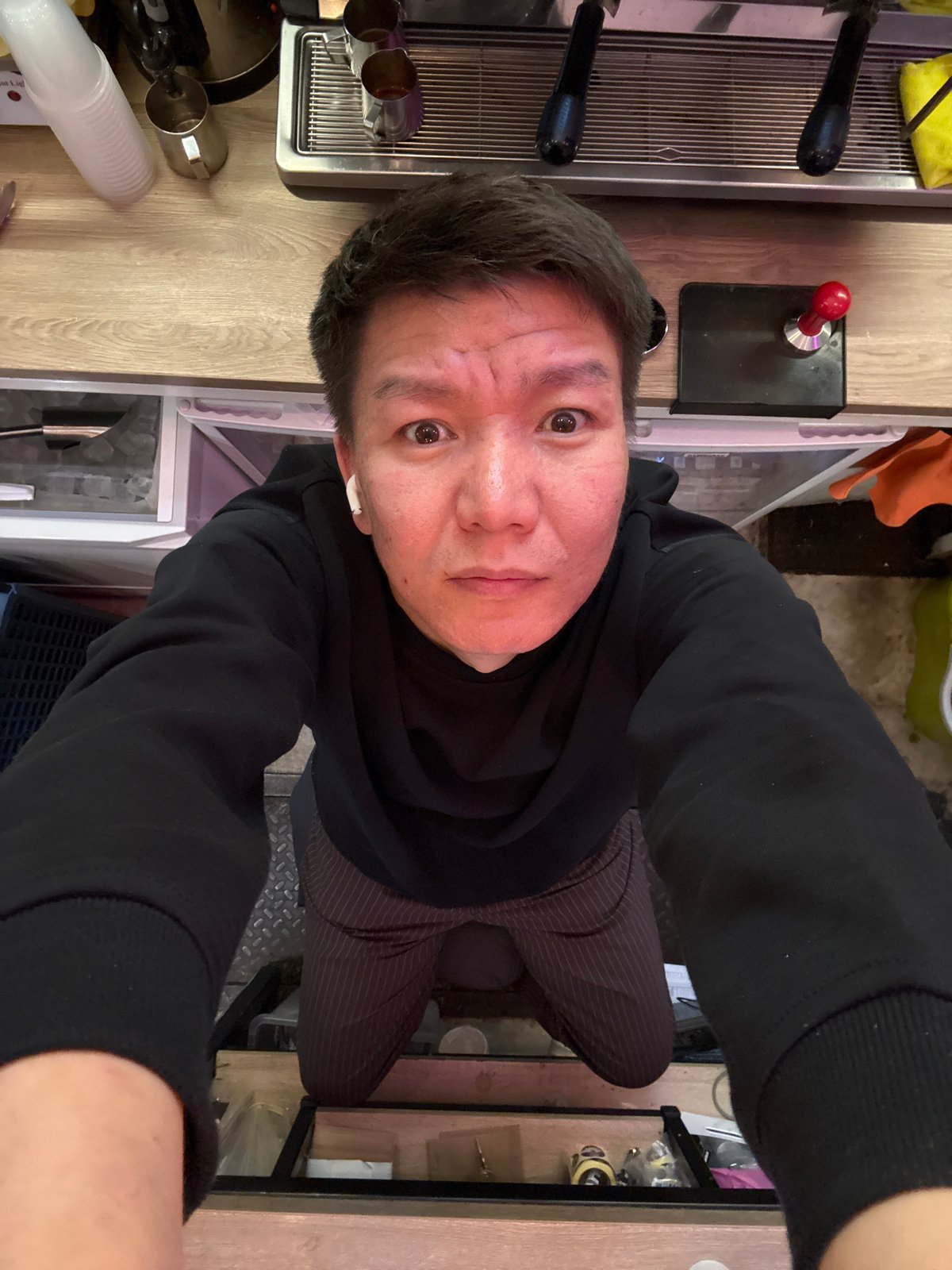 High-angle selfie in a café with espresso machine backdrop