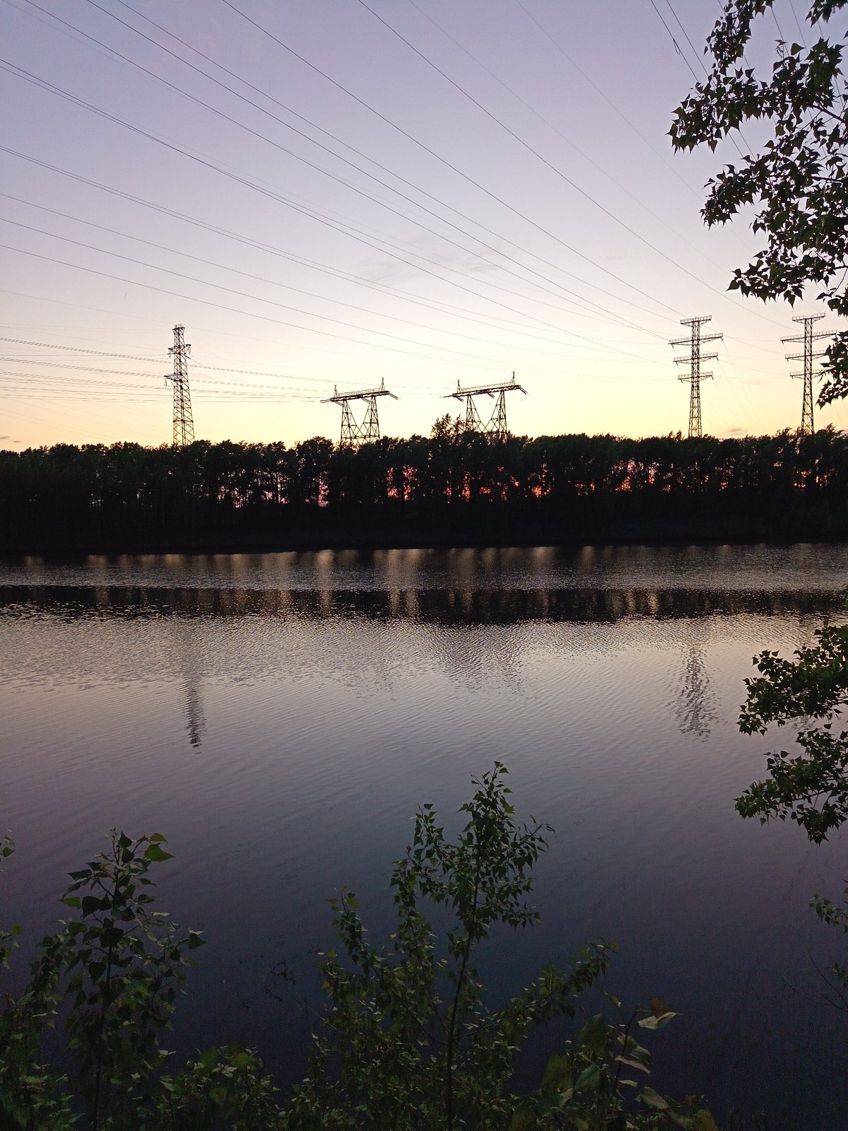 Peaceful waterside scene with power lines near Chaikovsky