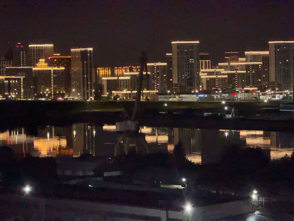 Tyumen's illuminated skyline reflects across the waterfront at night