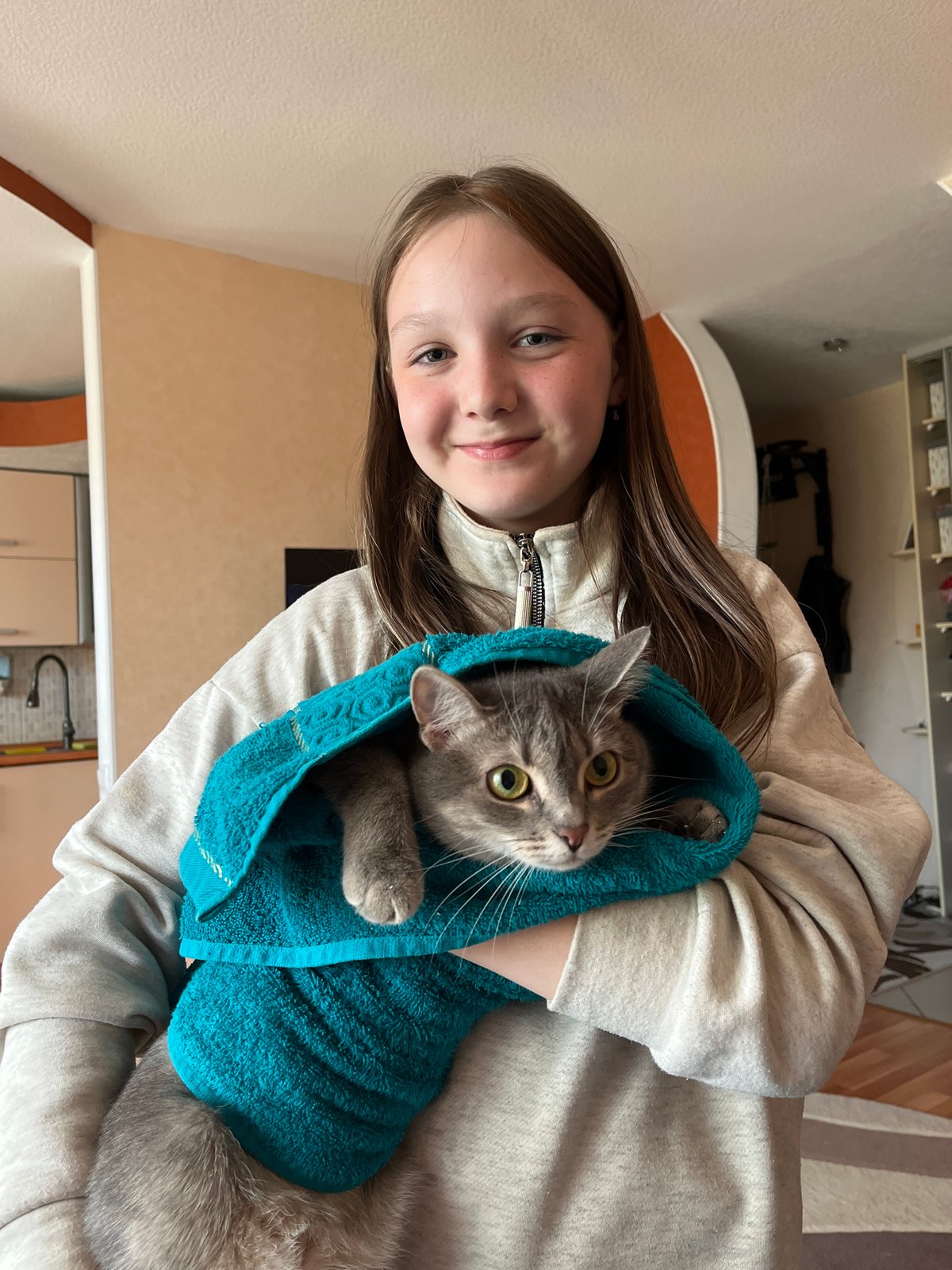 Woman holds gray cat in towel, Chaikovsky Russia