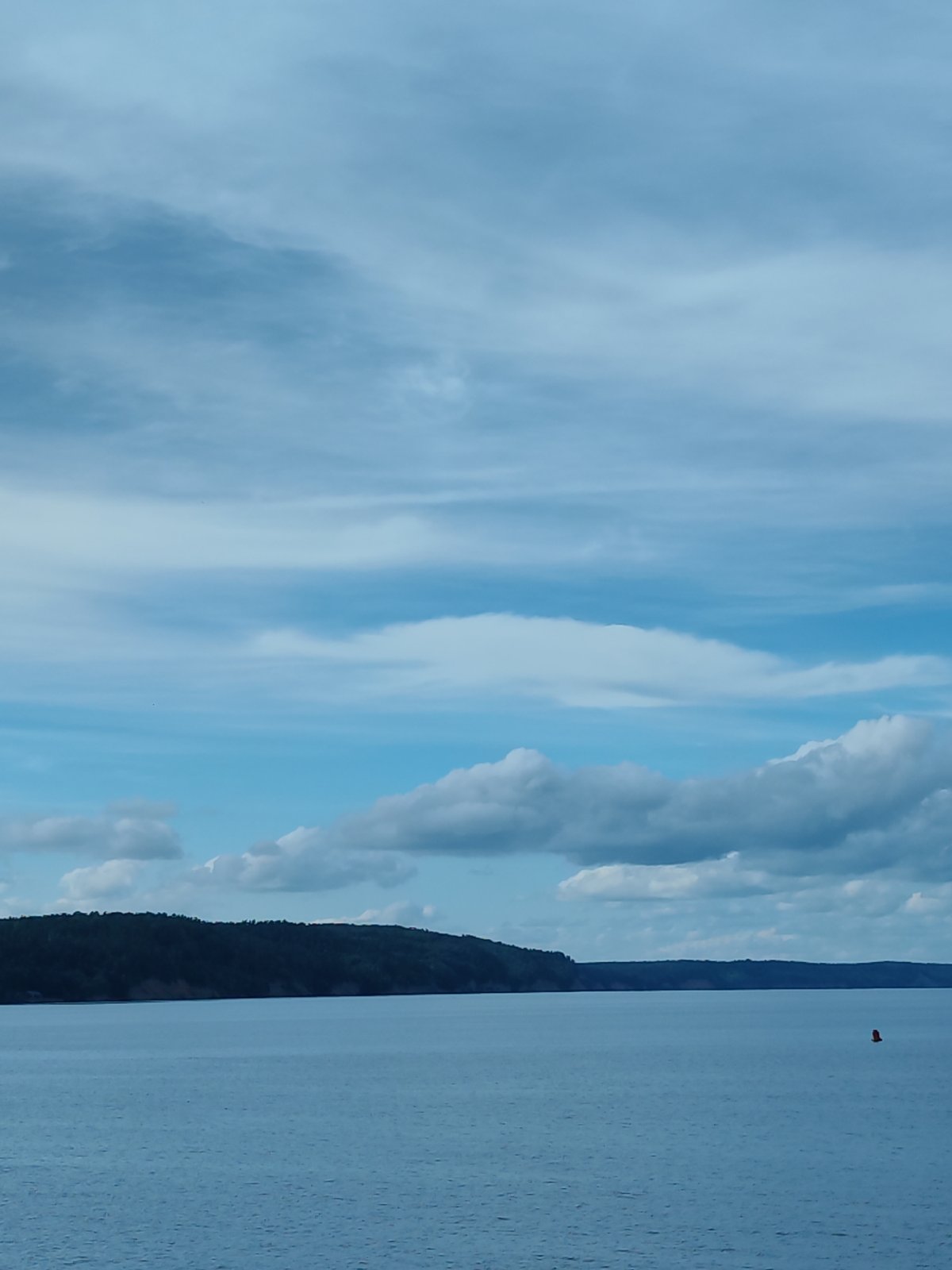 Calm waterway with distant shoreline and docked industrial vessels