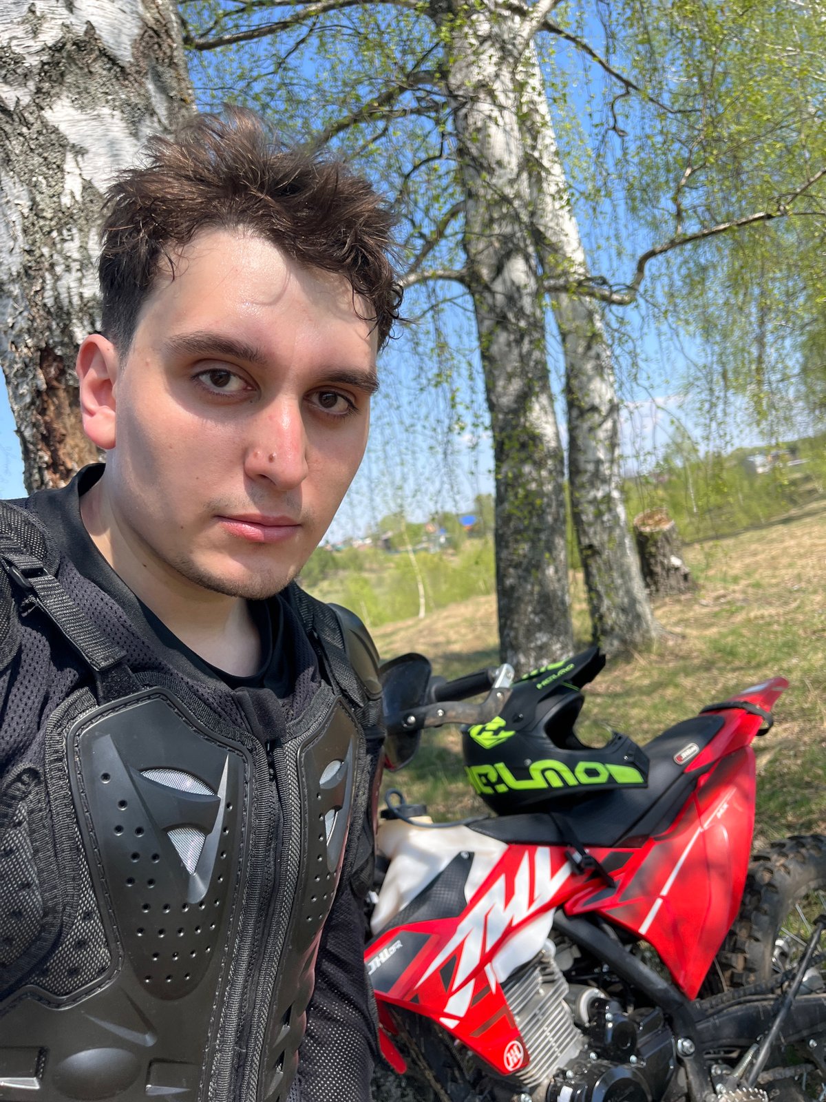 Motorcyclist poses with bike in Russian countryside spring scene