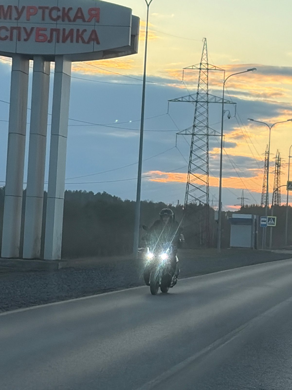 Motorcycle travels road in Chaikovsky, Russia near republic signage