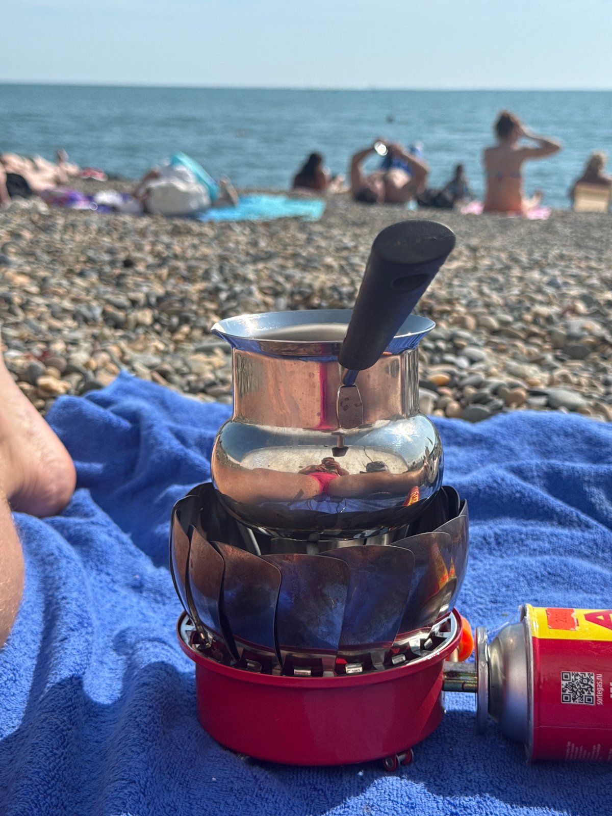 Beachgoer brews coffee on portable stove at Sochi beach