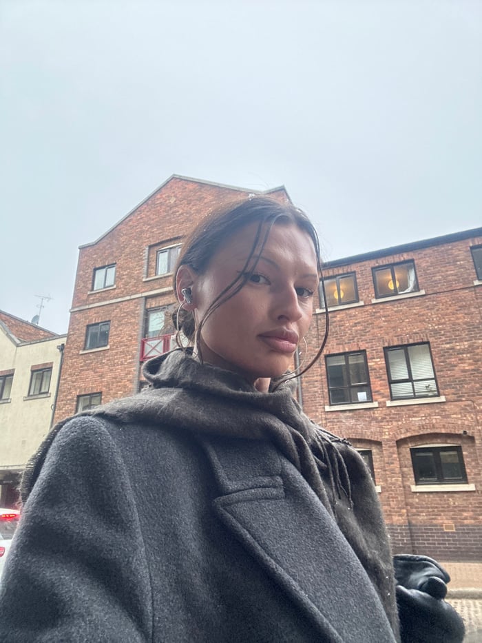 Woman observed in London snowfall wearing earbuds near vehicle