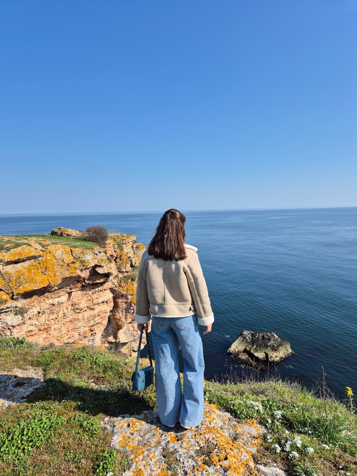 Woman photographs spring coastal scenery at Bulgarian Black Sea cliffs