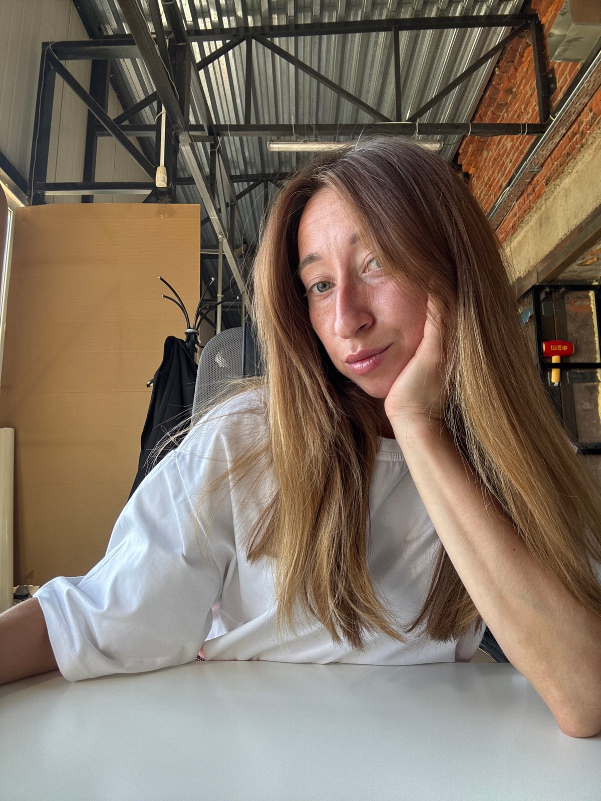 Woman sits at table in industrial space, Chaikovsky