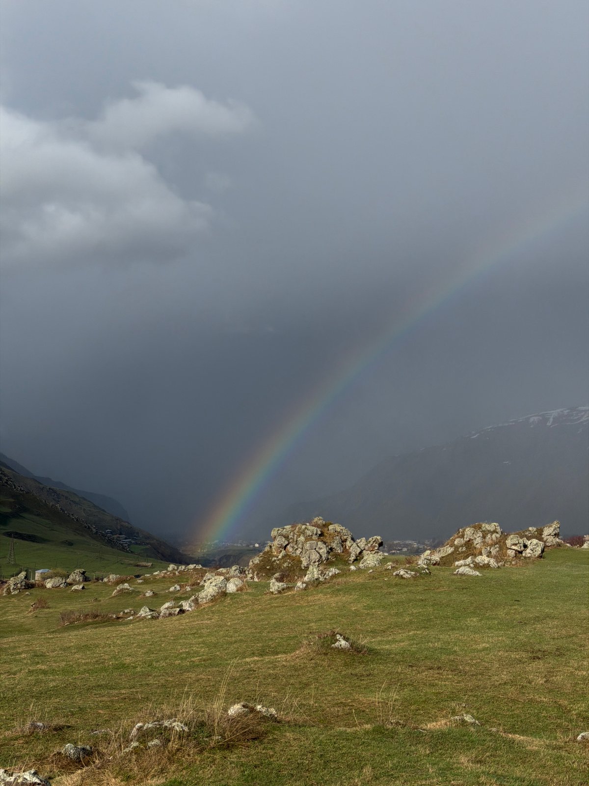 Rainbow appears over green hillside in Sioni, Georgia