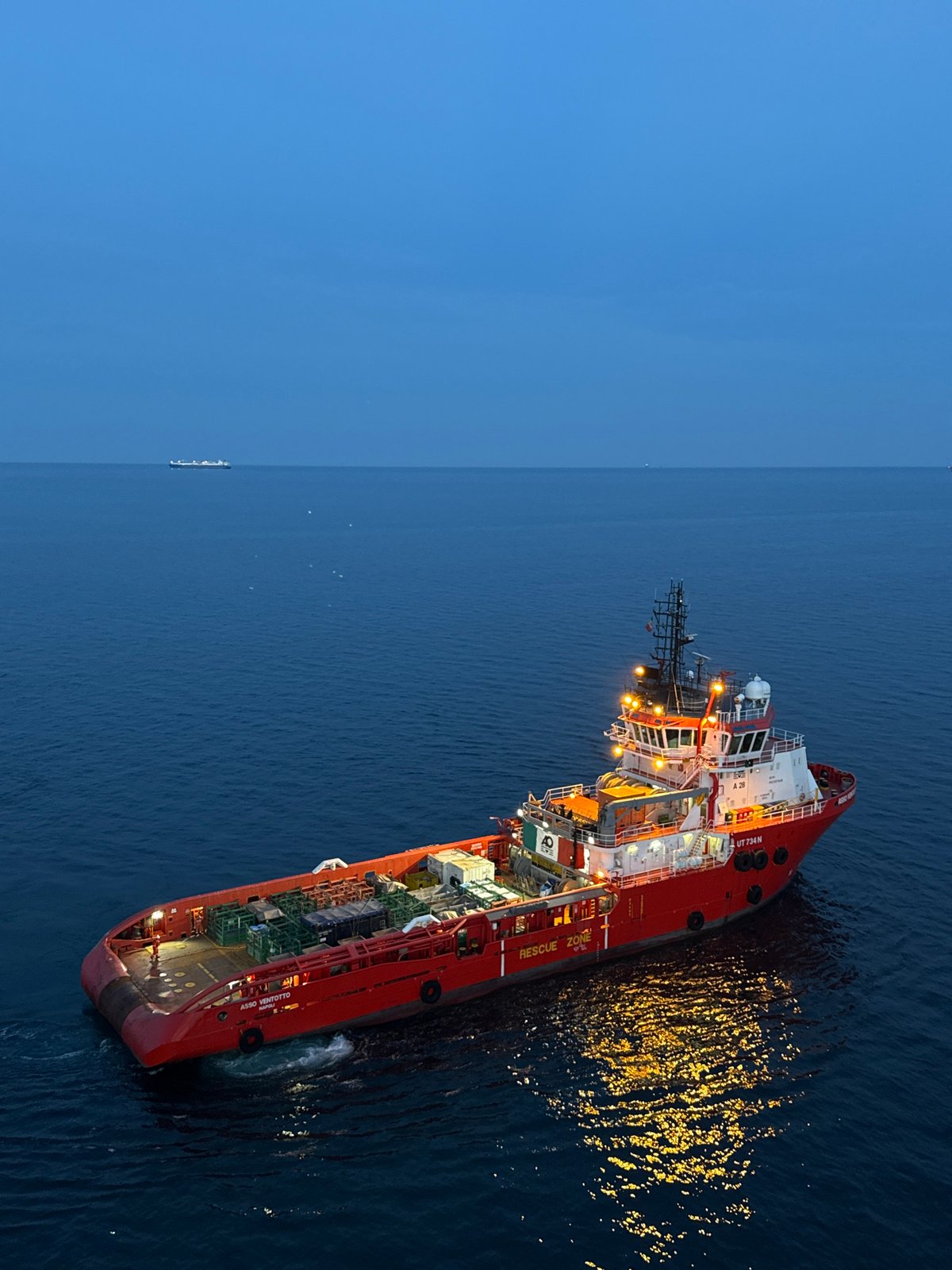 Offshore supply vessel works alongside Adriatic oil rig at dusk