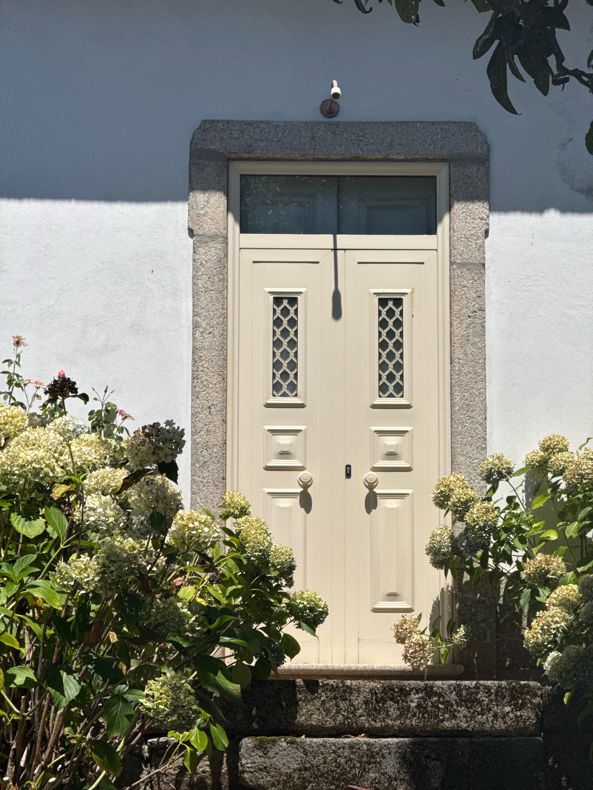Stone-arched doorway with latticed double doors in Alijó