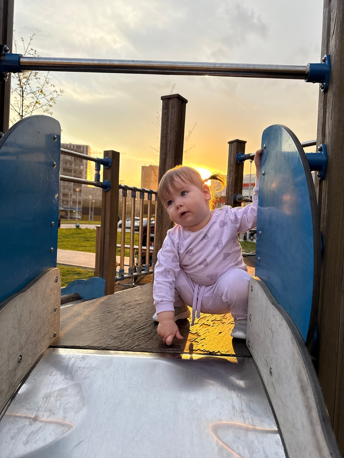 Baby plays on Moscow playground equipment in heart-patterned outfit