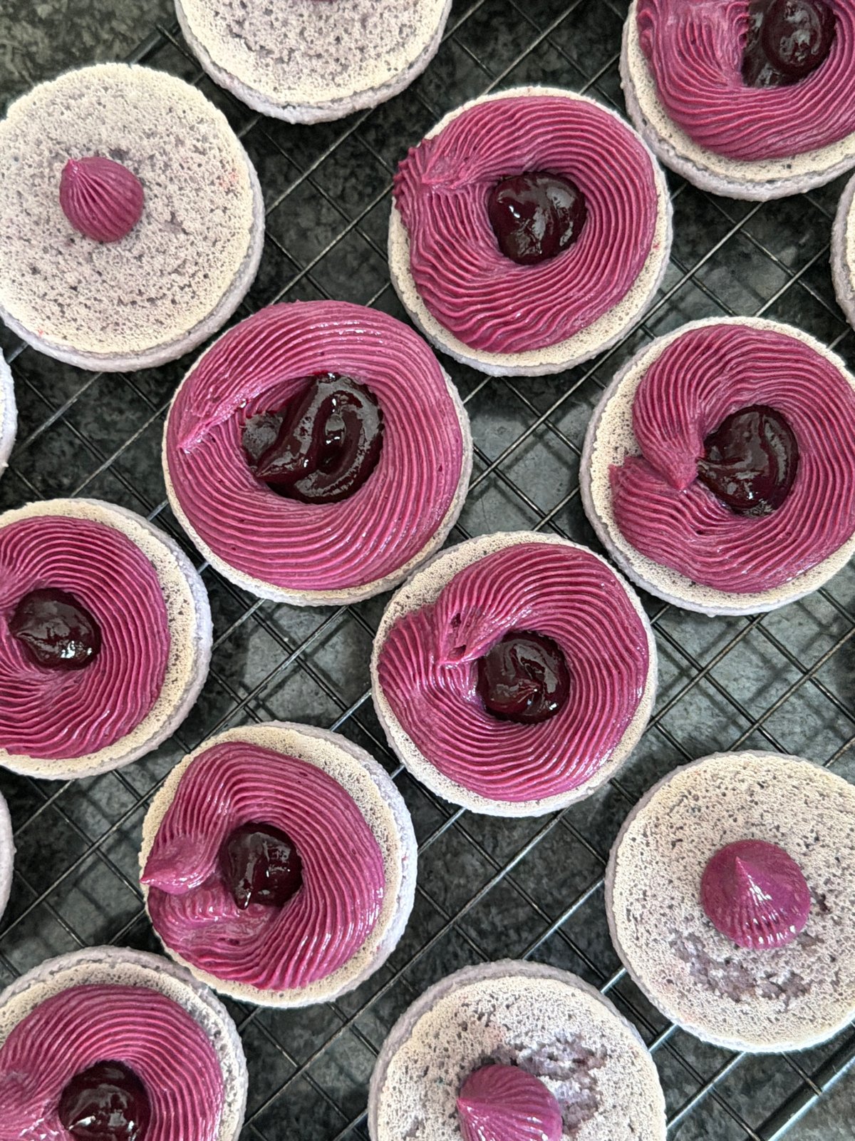 Baker decorates lavender macarons with purple frosting in Tel Aviv