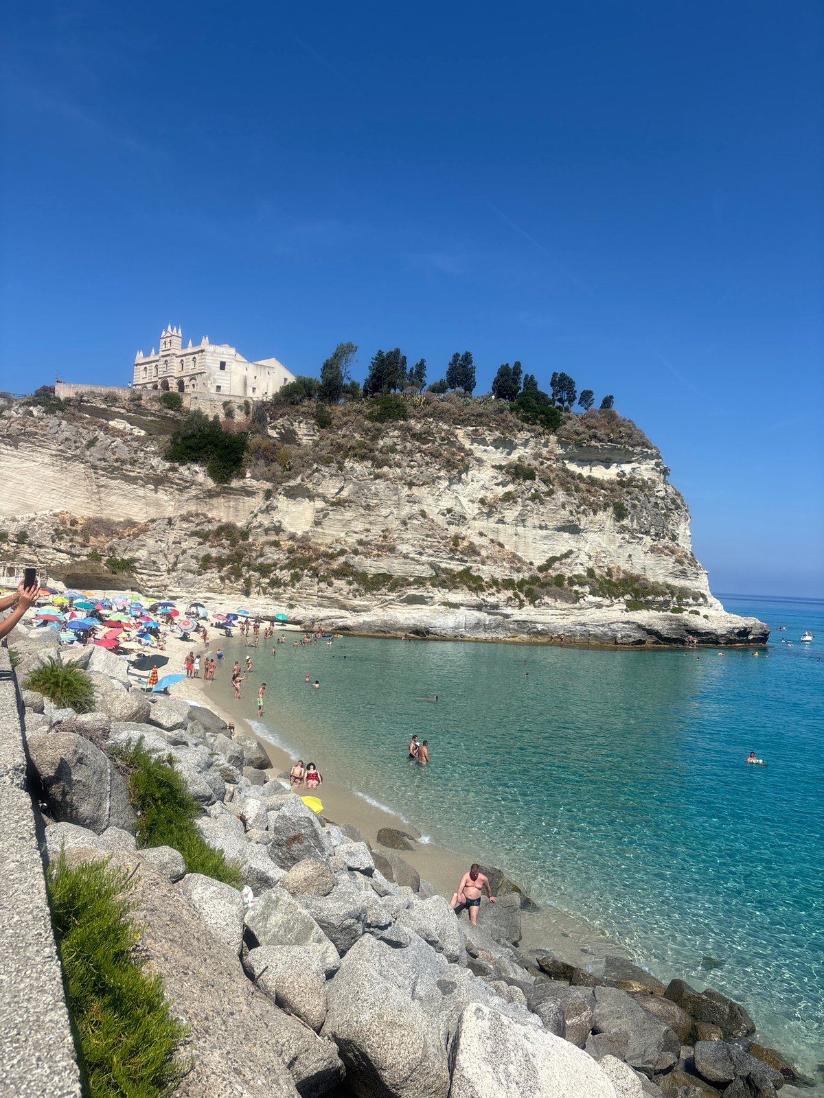Busy summer morning at Tropea beach beneath the clifftop sanctuary