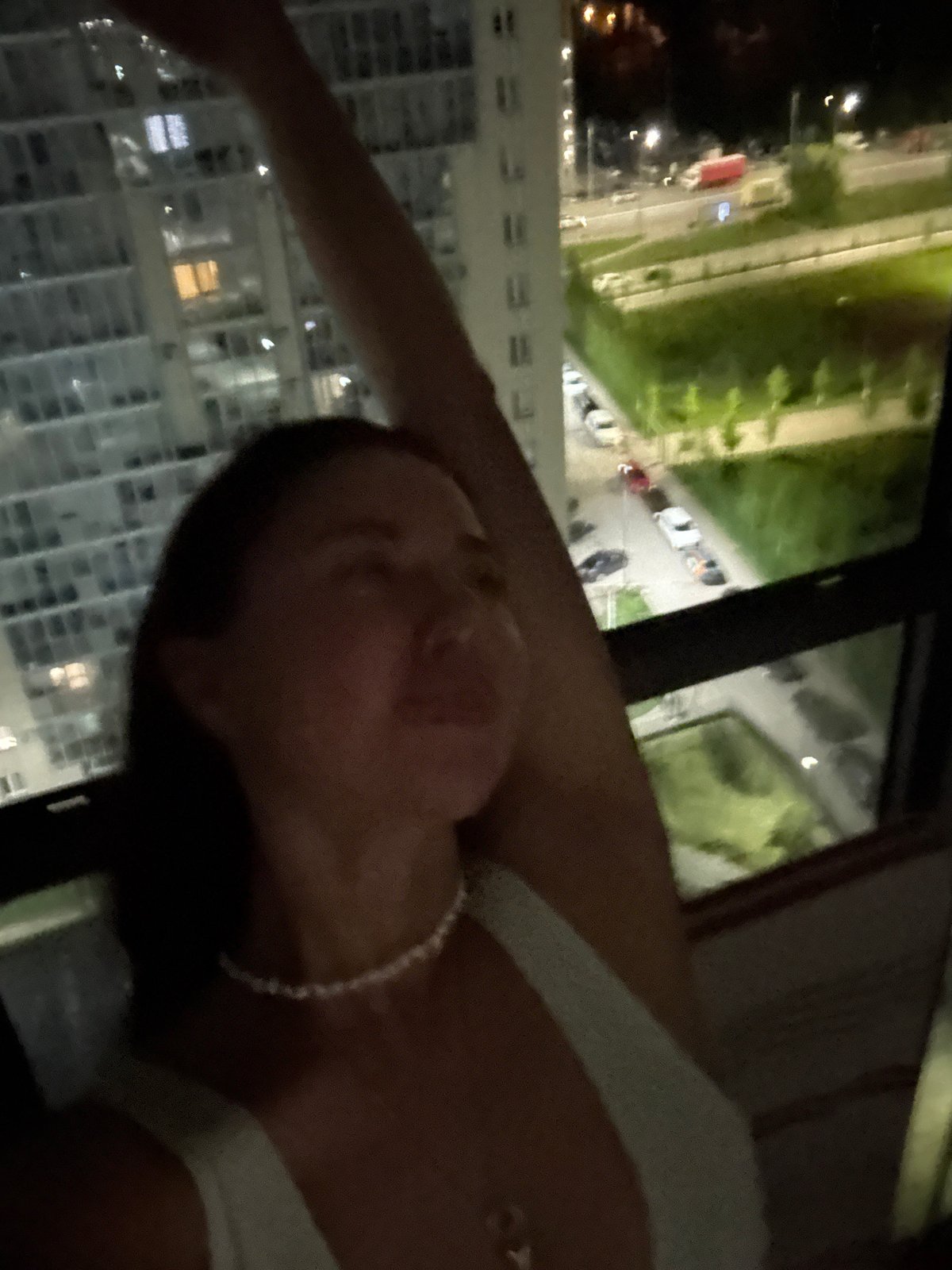 Person observes illuminated Kazan cityscape from indoor window