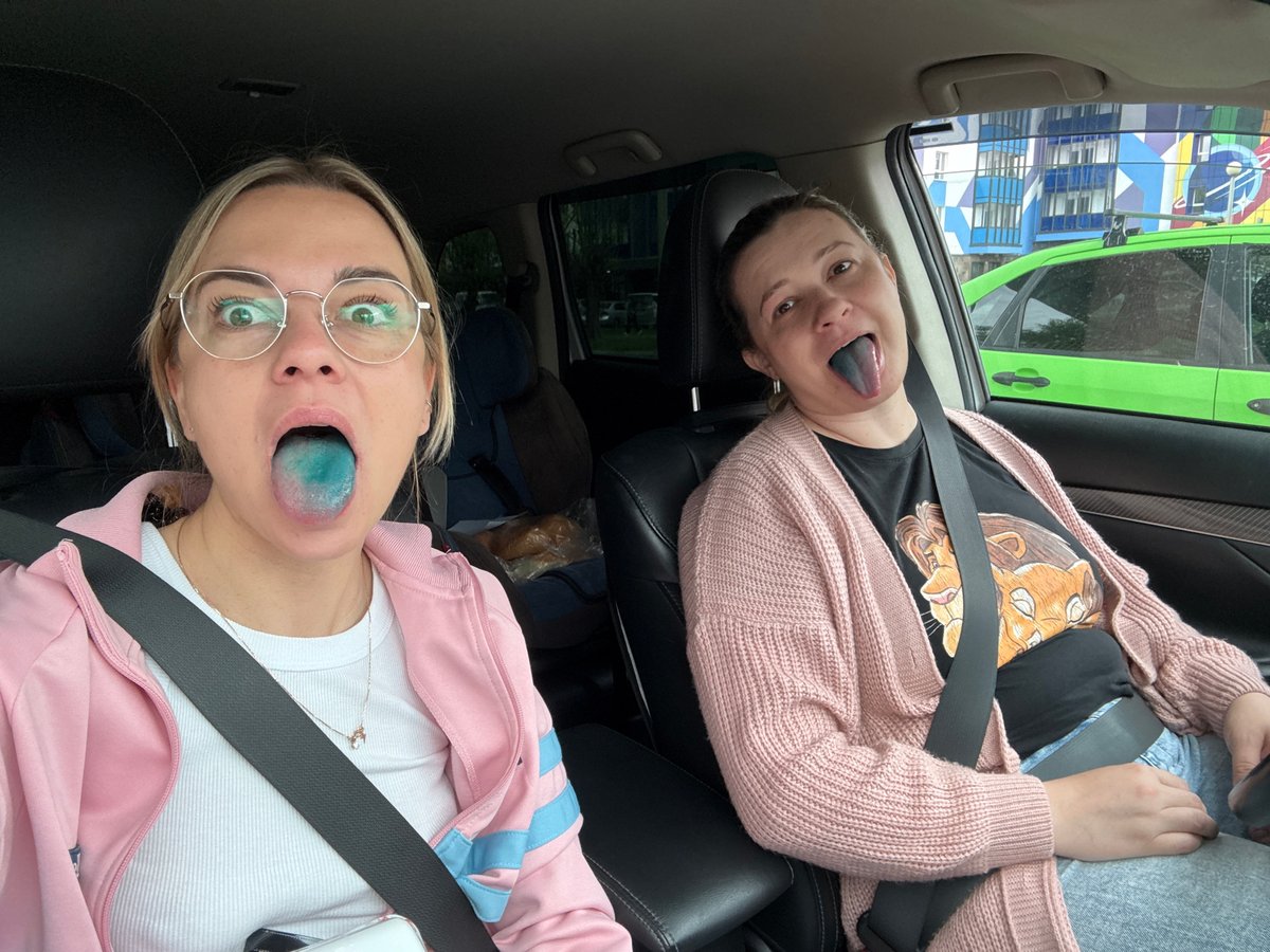 Two women show blue-stained tongues while seated in Krasnoyarsk car