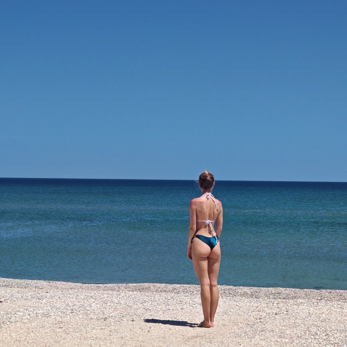 Beachgoers enjoy calm morning on shell-covered beach