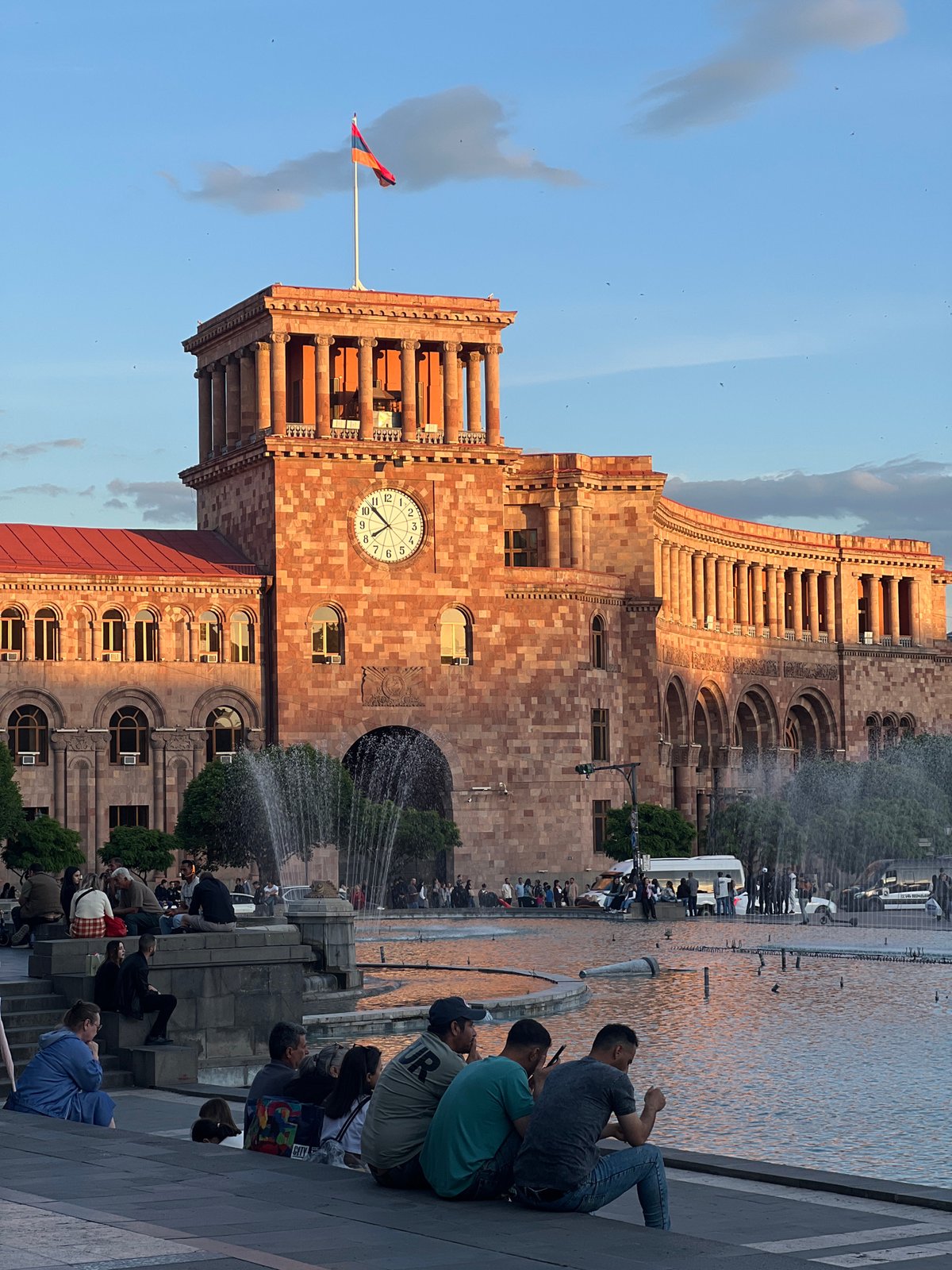 Clock tower with Armenian flag observed near public fountain