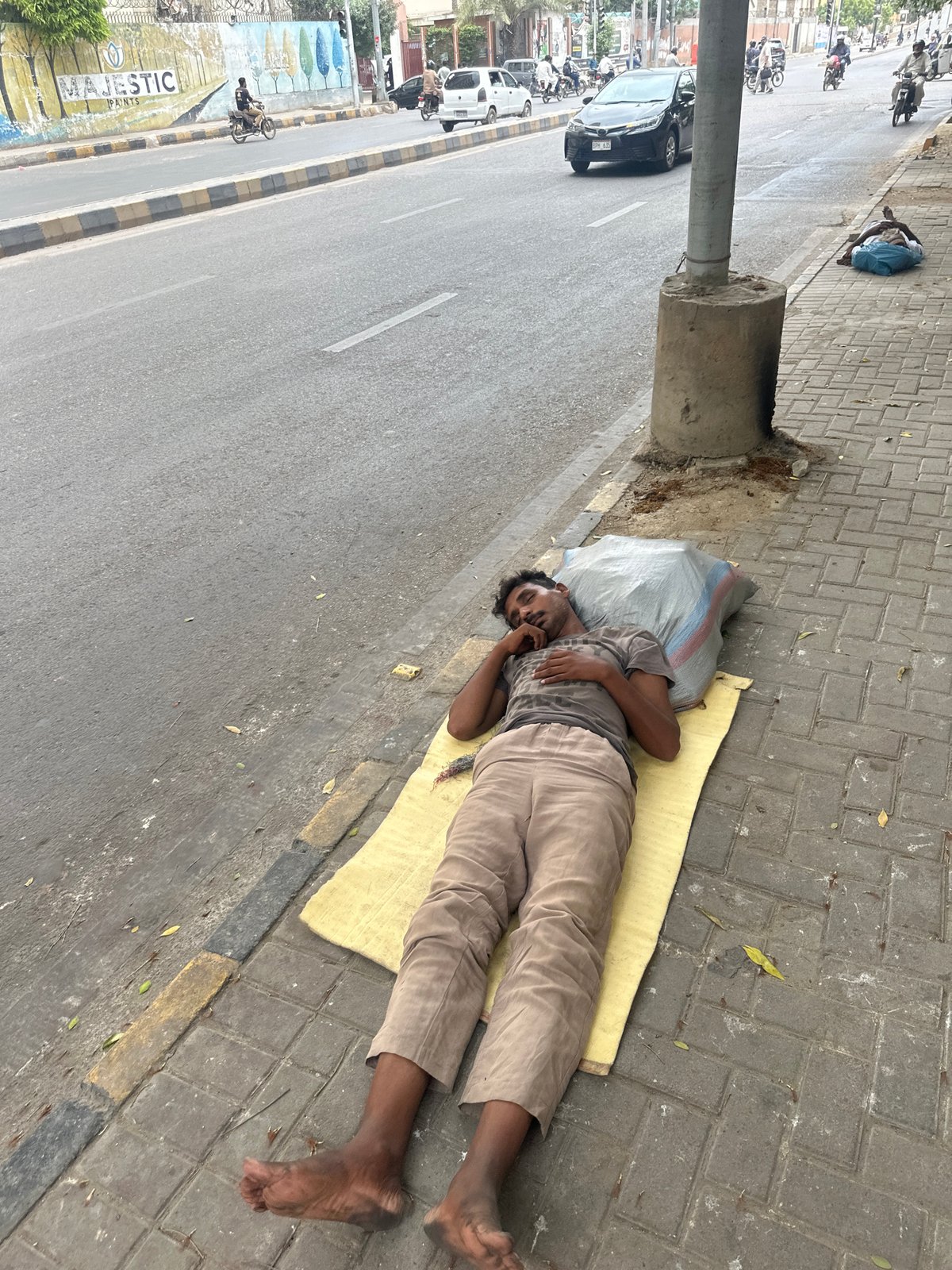 Sleeping on Karachi sidewalks on a July morning