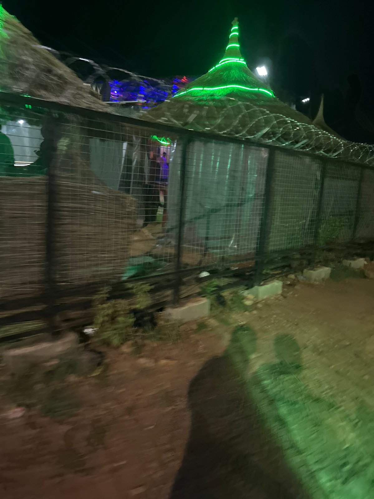 Illuminated tower structure observed behind fence in Jos, Nigeria