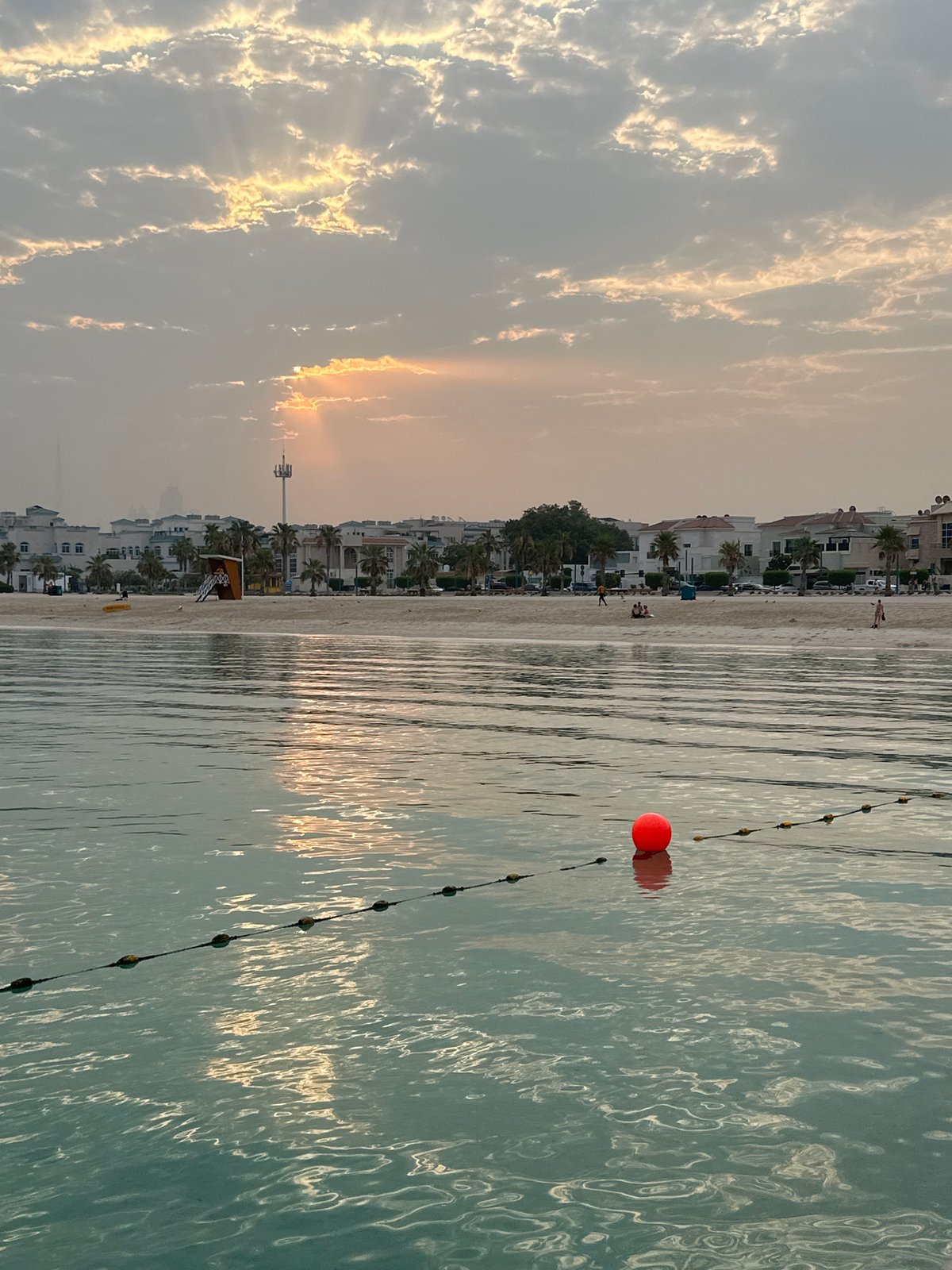 Dubai beachfront at golden hour, calm water and cloudy skies