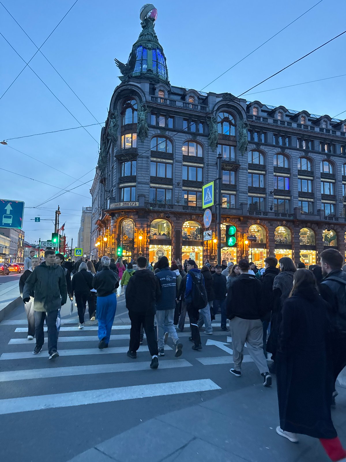 Evening pedestrian crowds cross streets near Saint Petersburg landmarks