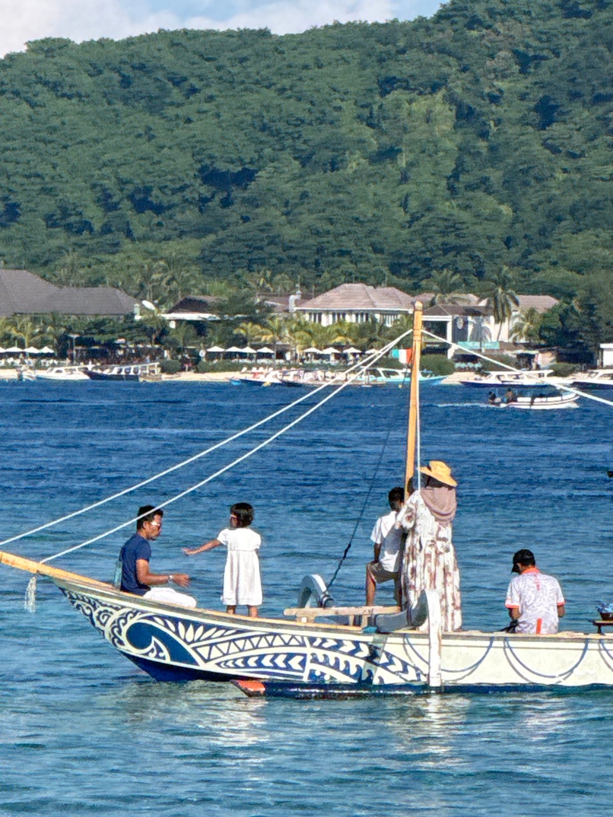 Traditional outrigger canoe navigates Indonesian coastal waters with crew