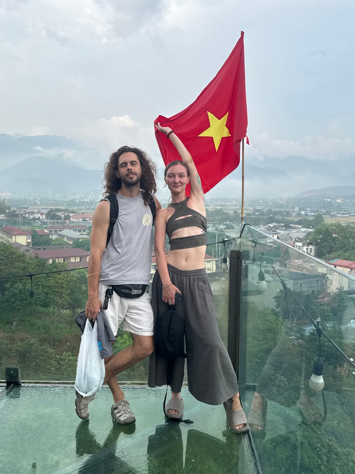 Tourists pose with Vietnamese flag on glass viewing platform