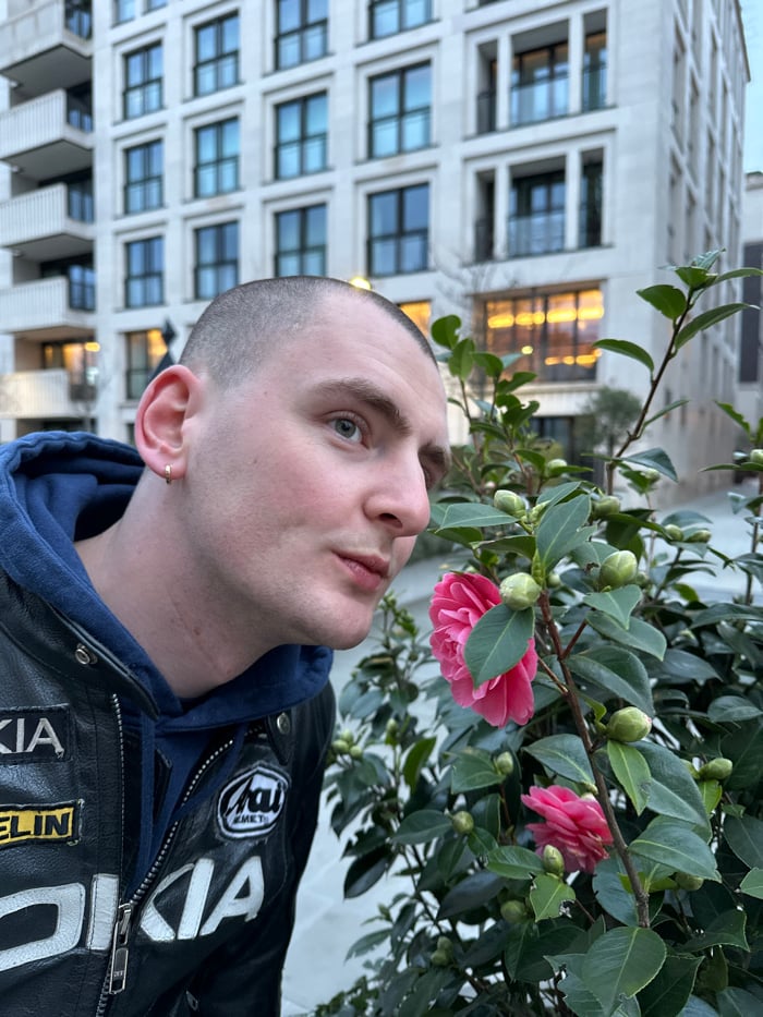Man poses with blooming camellias in London