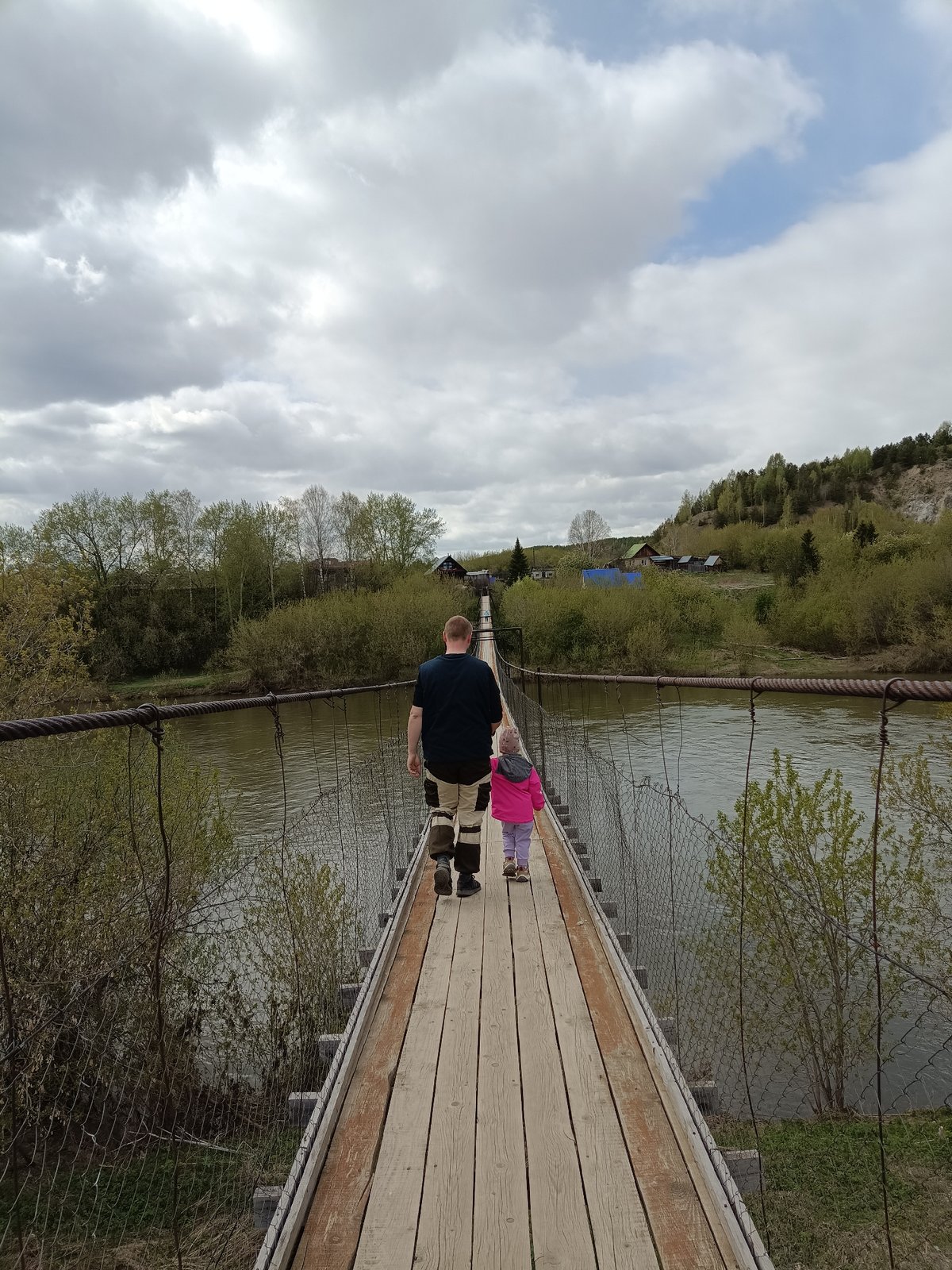 Adult and child cross wooden bridge in Russian town