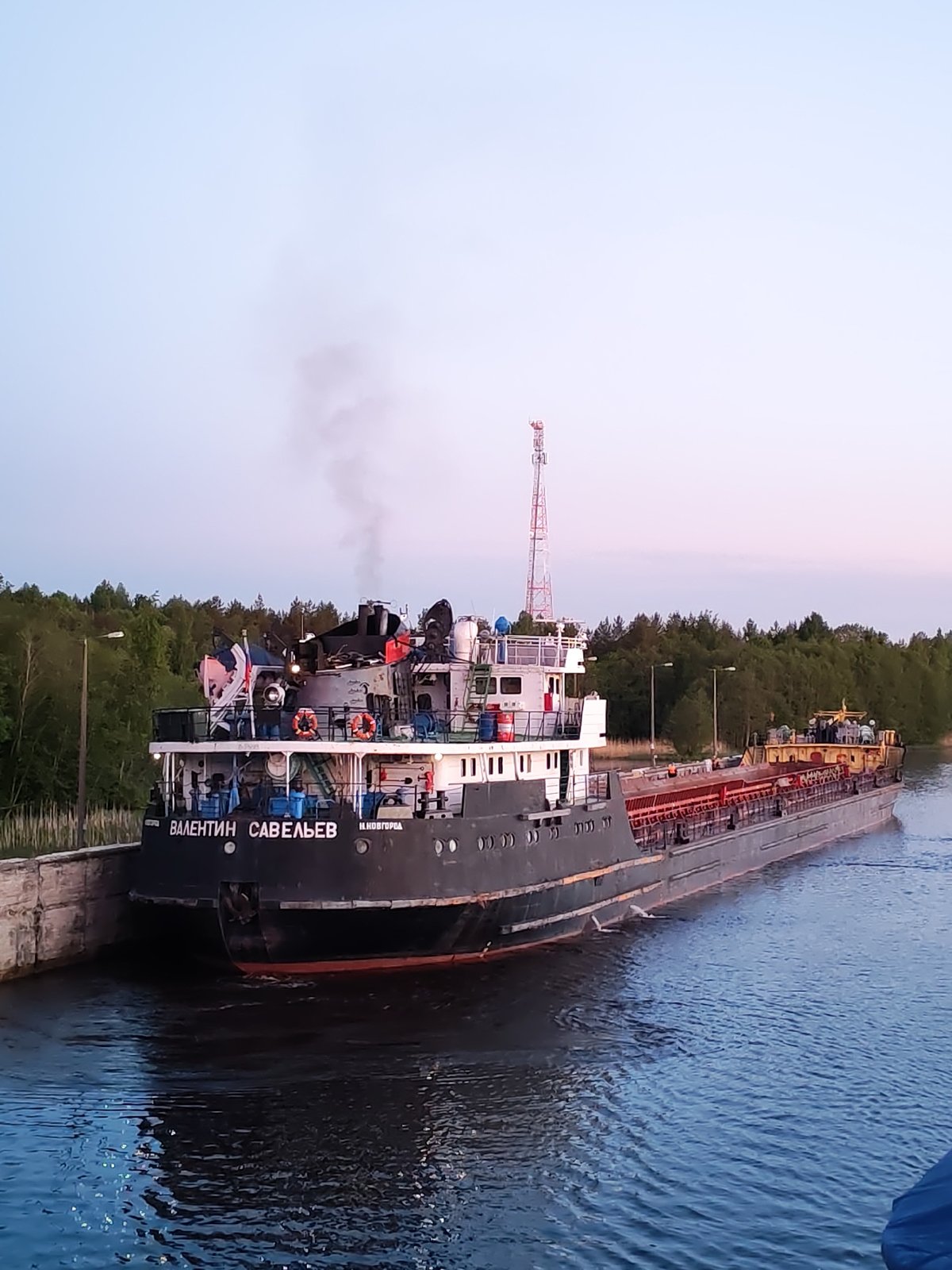 Cargo ships transit Russian waterways near Devyatiny at twilight