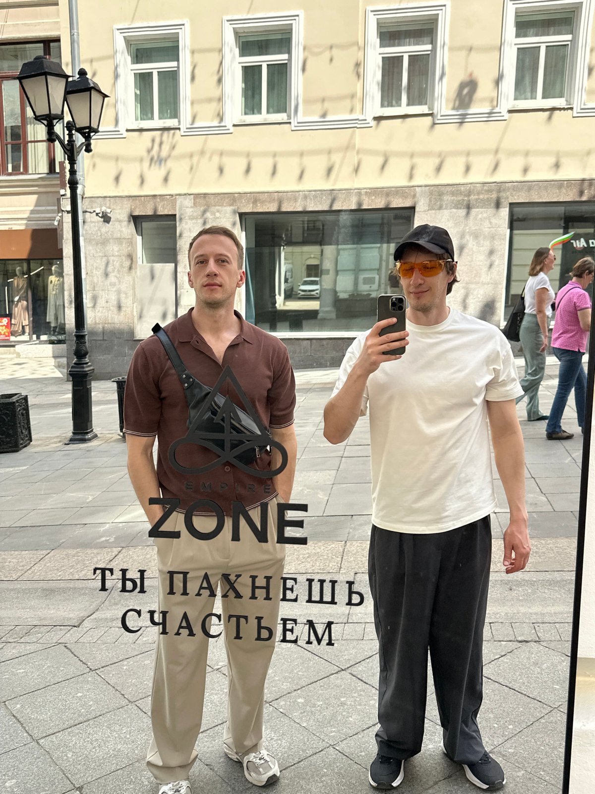 Two men take selfies at Moscow storefront mirror