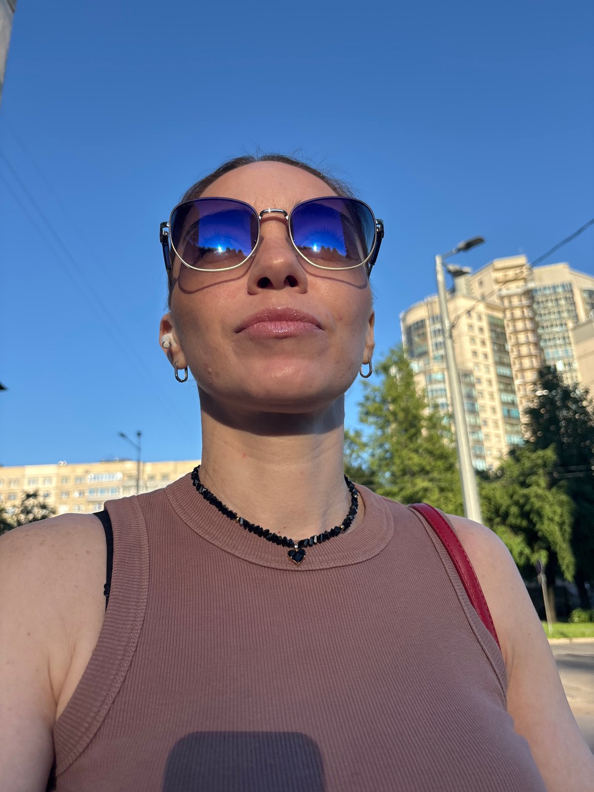 Woman photographed outdoors in Sinyavino wearing blue sunglasses