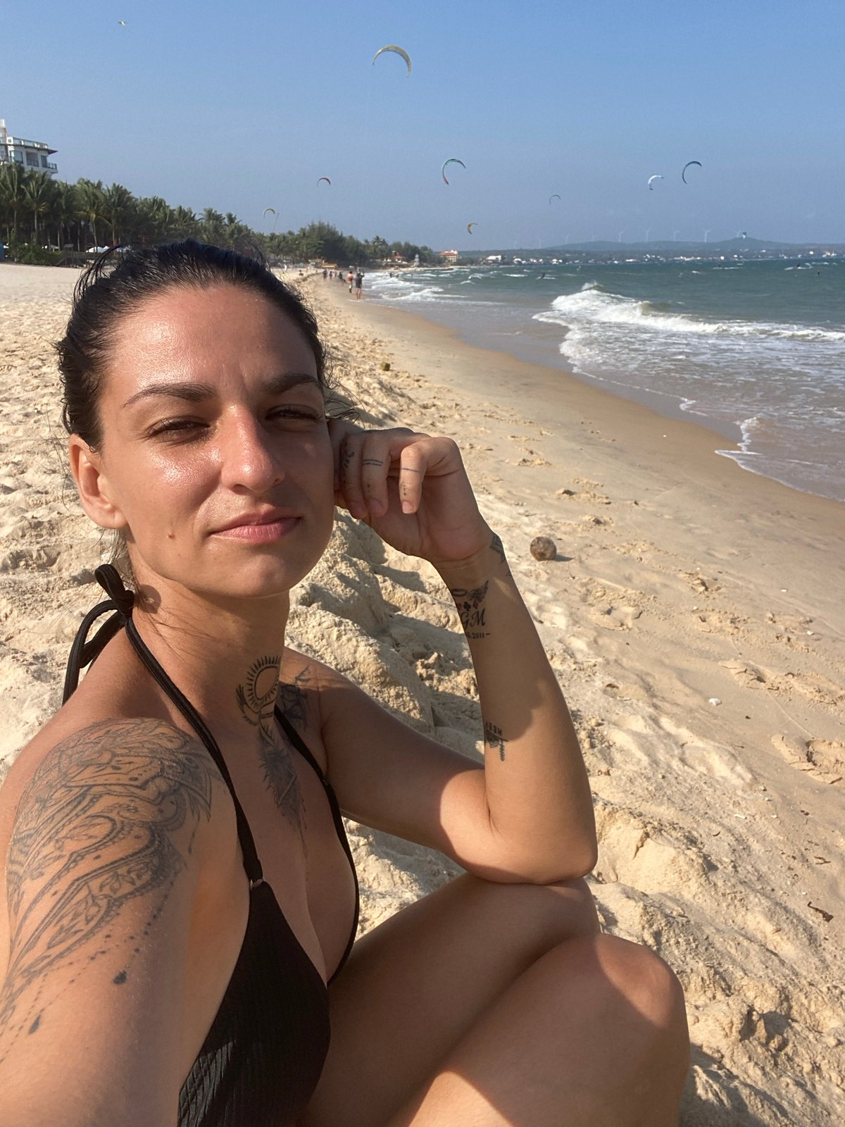 Beach day captured: woman sunbathing, kitesurfer, dog at Vietnam shore