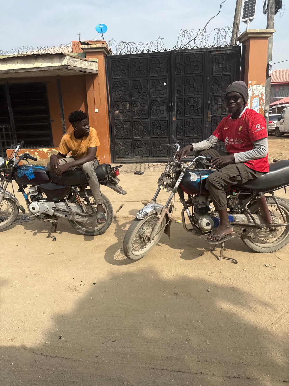 Two men with motorcycles spotted on dusty road in Ado, Nigeria