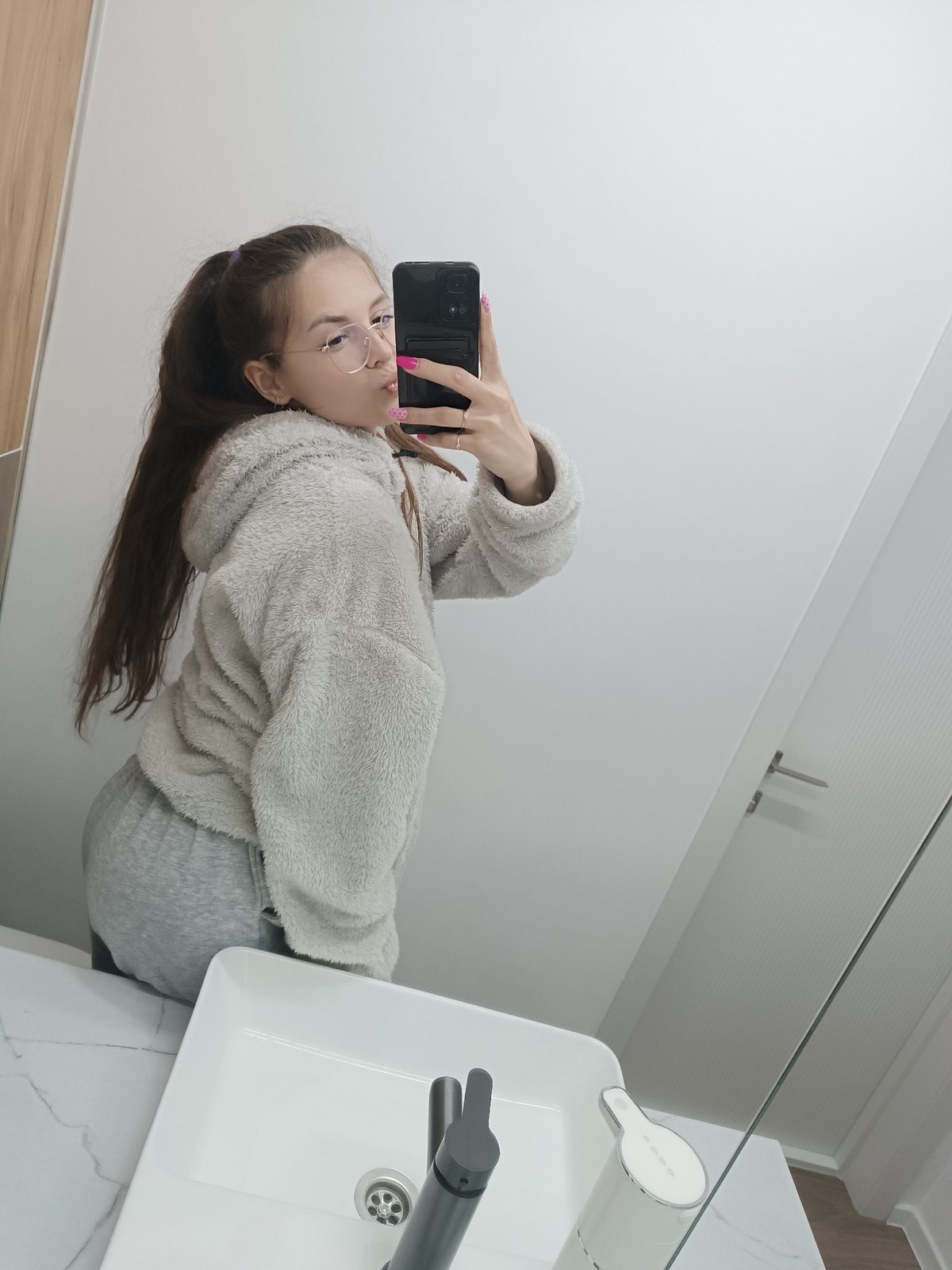 Woman takes bathroom selfie in gray outfit