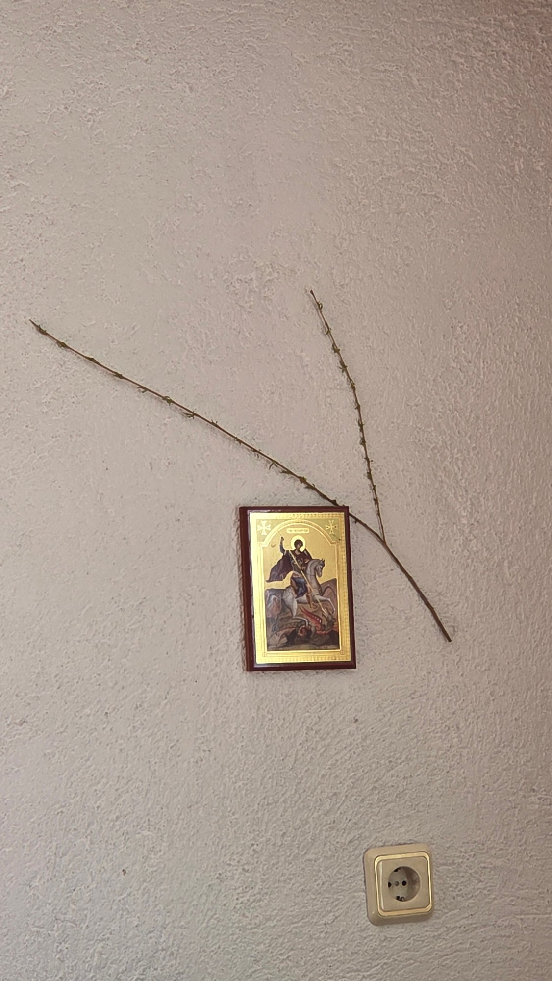 Religious icon displayed on textured wall with mounted items