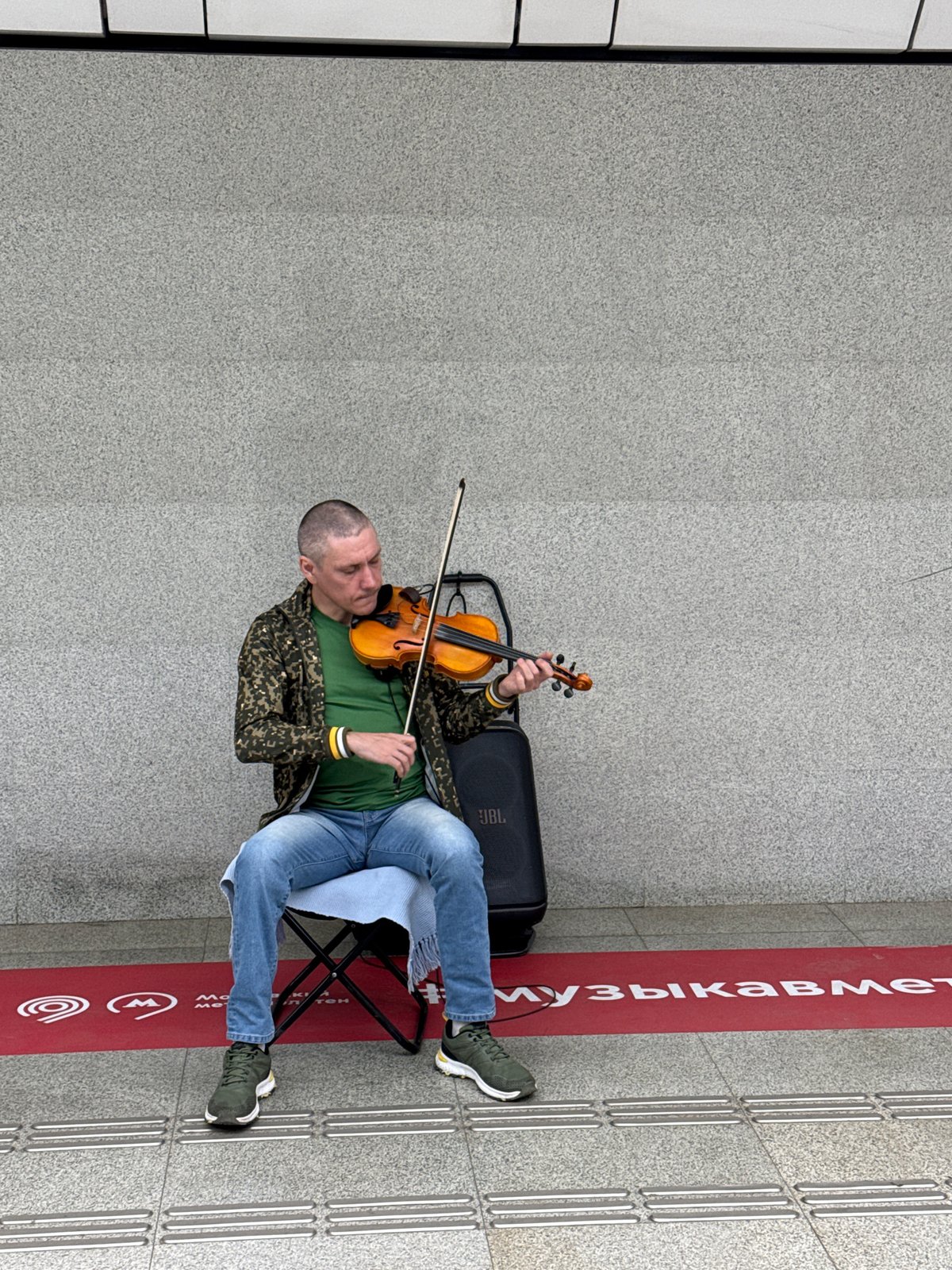 Street violinist performs in Moscow; photo album reviewed nearby