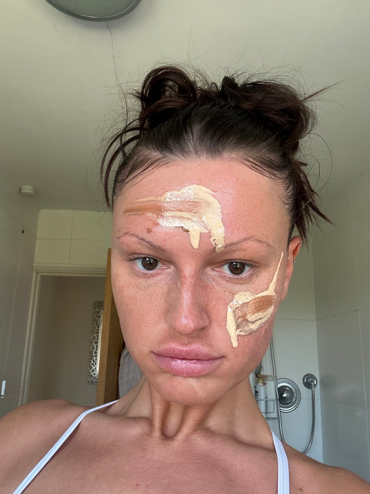 Woman applies makeup in bathroom, Wealden UK morning routine