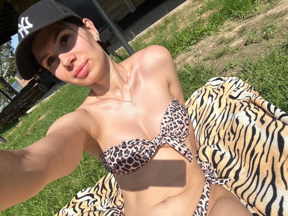 Woman sunbathes on tiger-print blanket in grassy urban area
